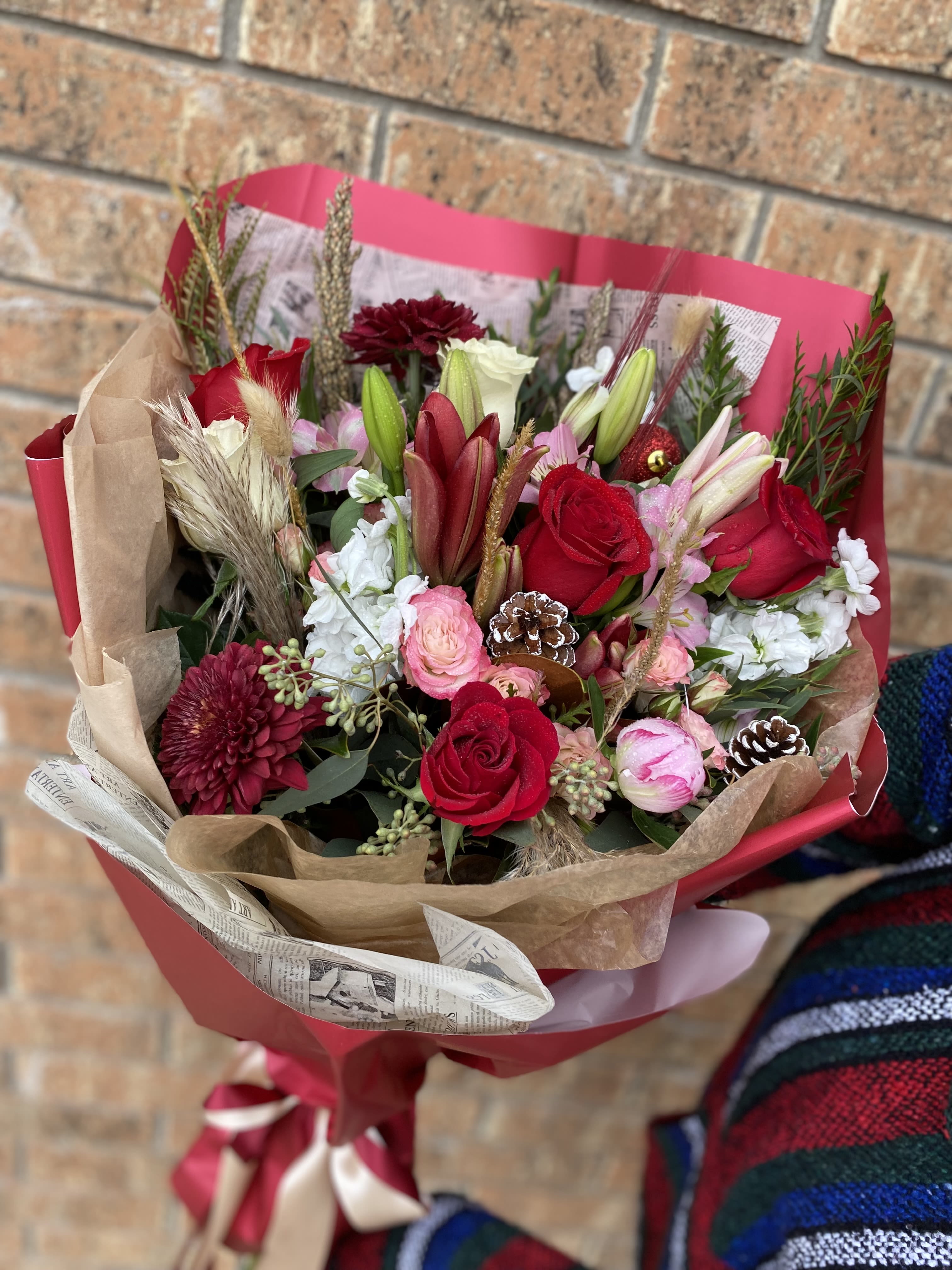 Christmas Kisses  - Christmas’s Kisses is a sweet, festive arrangement designed to capture the warmth and romance of the holiday season. Rich red blooms—like roses, carnations, or holiday chrysanthemums—are paired with snowy white flowers to create a classic Christmas palette. Fresh evergreens, pinecones, and sparkling seasonal accents add texture and charm, while a holiday ribbon finishes the look with a touch of elegance. Perfect for gifting or decorating, this arrangement delivers the cozy, heartfelt feeling of Christmas in every petal.