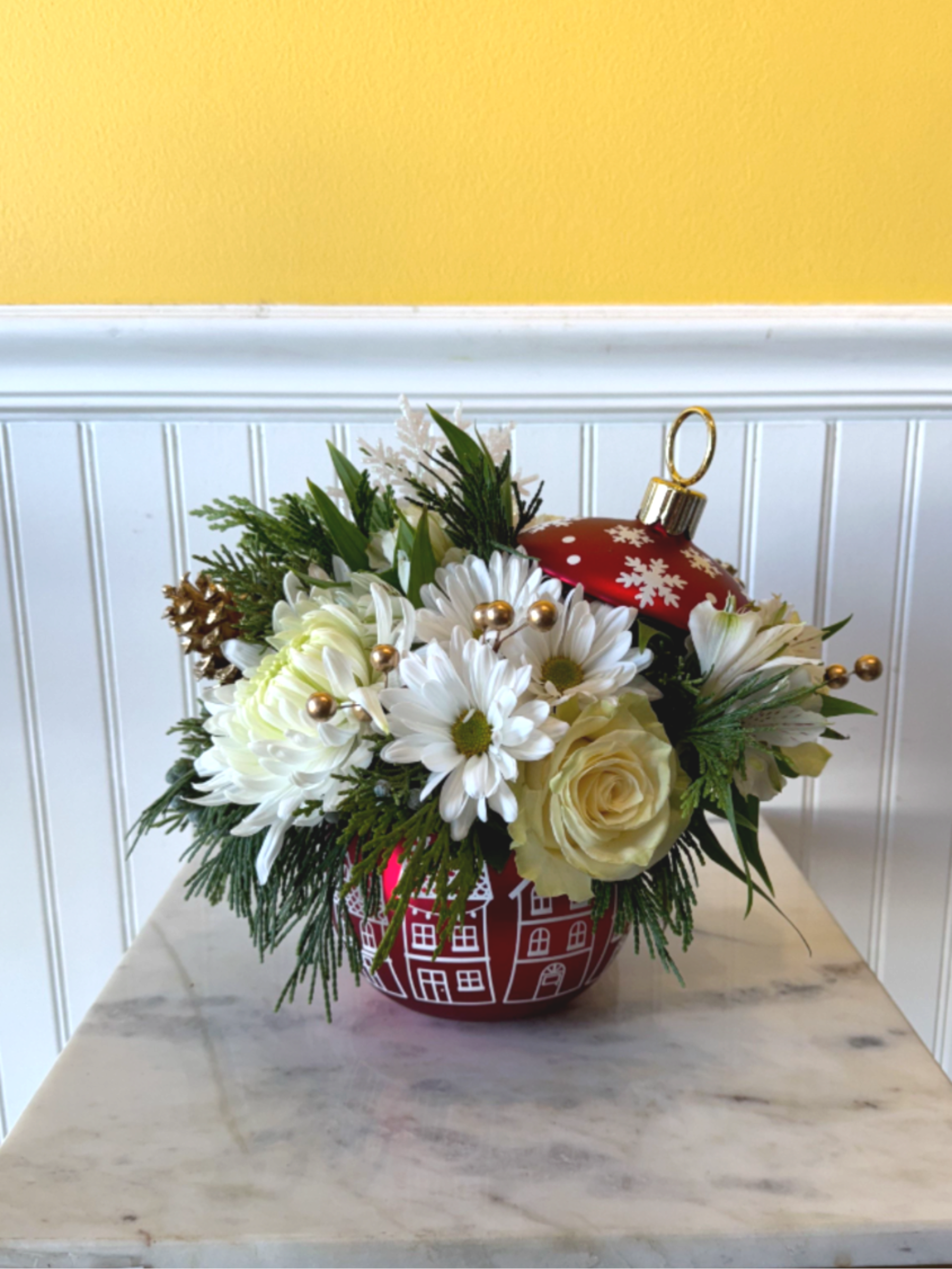 Holiday Cheer - Bring the magic of the season home with Holiday Cheer—a festive burst of joy nestled in a charming ornament-inspired container. This arrangement sparkles with wintry elegance and warm holiday spirit, perfect for gifting or brightening your own space. Let it be the centerpiece of your celebration, where tradition meets delight. Approx dimension 10 X 12 inch