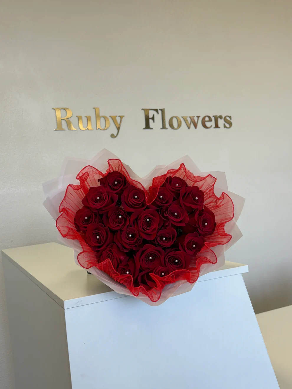 HEART 20 RED ROSES BOUQUET - stunning heart-shaped arrangement of deep red roses, elegantly wrapped with sheer white and red mesh. Each rose is accented with a delicate pearl detail, creating a luxurious and romantic look — perfect for expressing love in the most beautiful way.”