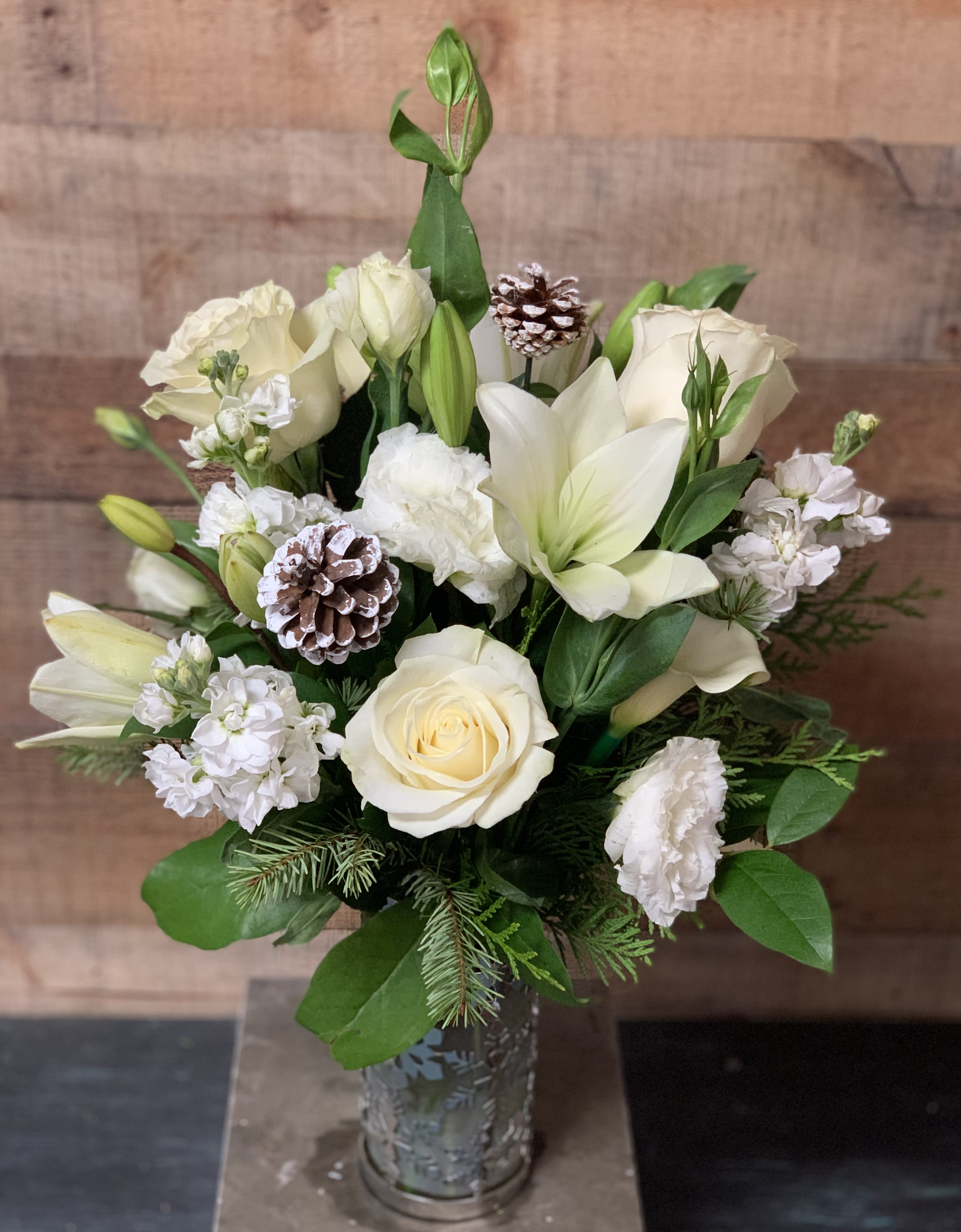 White Christmas - All white flower arrangement with Pinecones in a clear vase