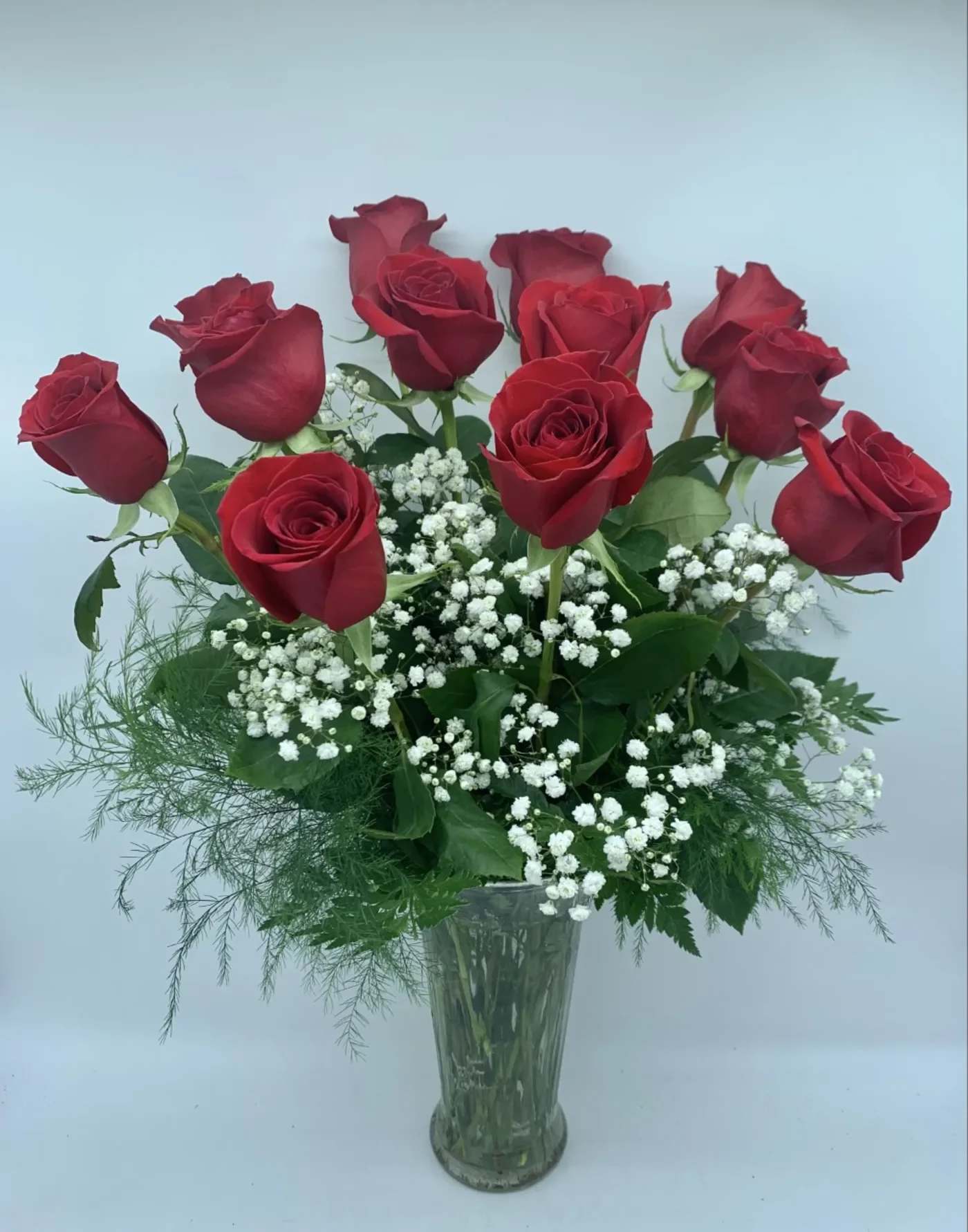 CLASSIC RED ROSES OF LOVE   $100/150/200 -   This bouquet of one dozen long stem premium, florist grade Red Roses is adorned with a classic mix of white baby’s breath and ferns.  They are the classic gift of love.  Upgrade to eighteen Deluxe or two dozen Premium.  These are 60 cm roses and the arrangement measures approx 24" high.   Finishing touches include fragrant candles, Teddy Bear Plush, Chocolates and even our Vintage Brooch collection.