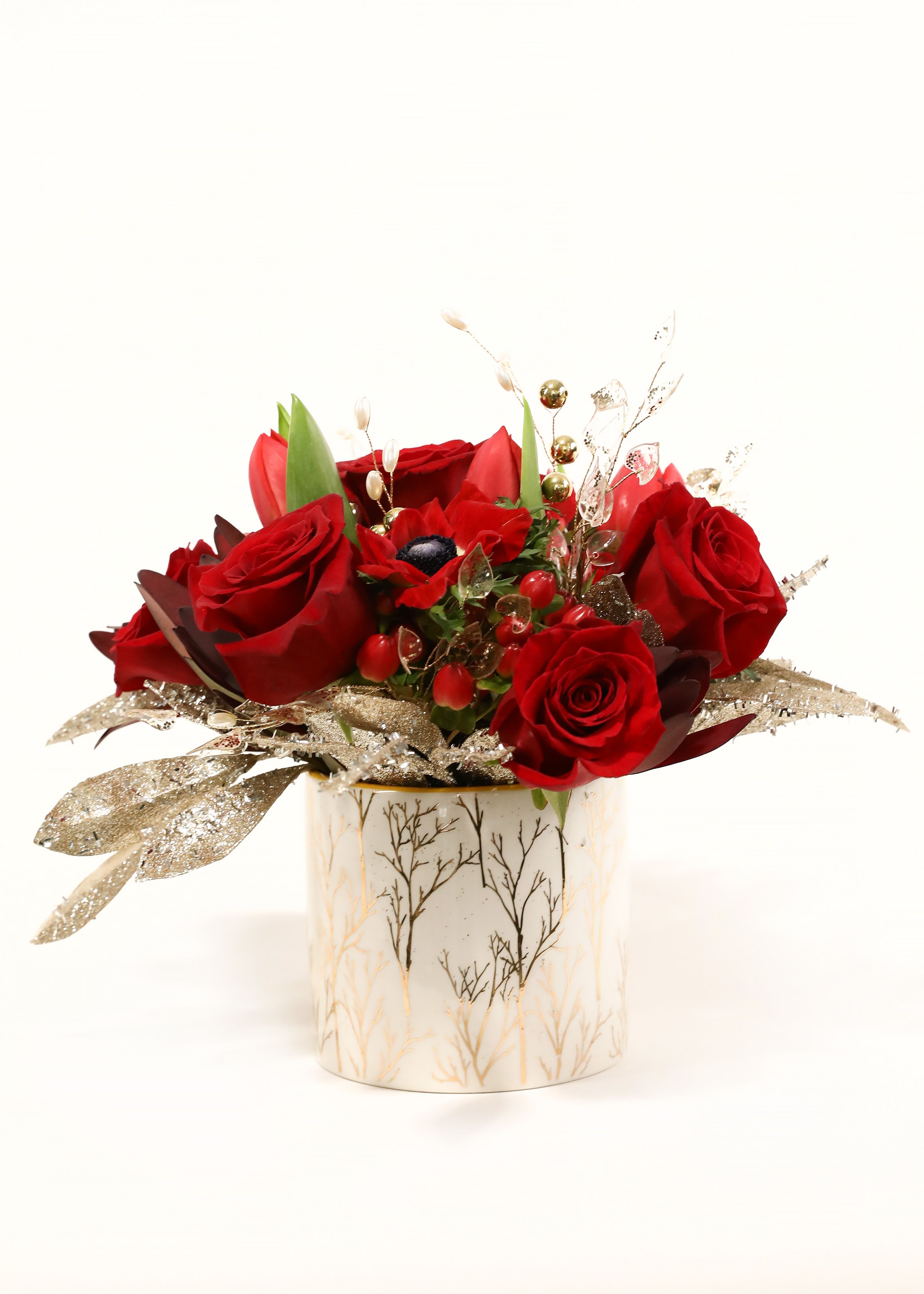 A GOLDEN NOEL - THIS ARRANGMENT IS PERFECT TO PUT ANYONE IN THE CHRISTMAS SPIRIT. IT HAS MULTIPLE RED FLOWERS AND IS ADORNED WITH SPARKLY GOLD LEAVES TO MATCH THE GOLD BRANCHES ON THE WHITE CYLINDER GLASS VASE. 