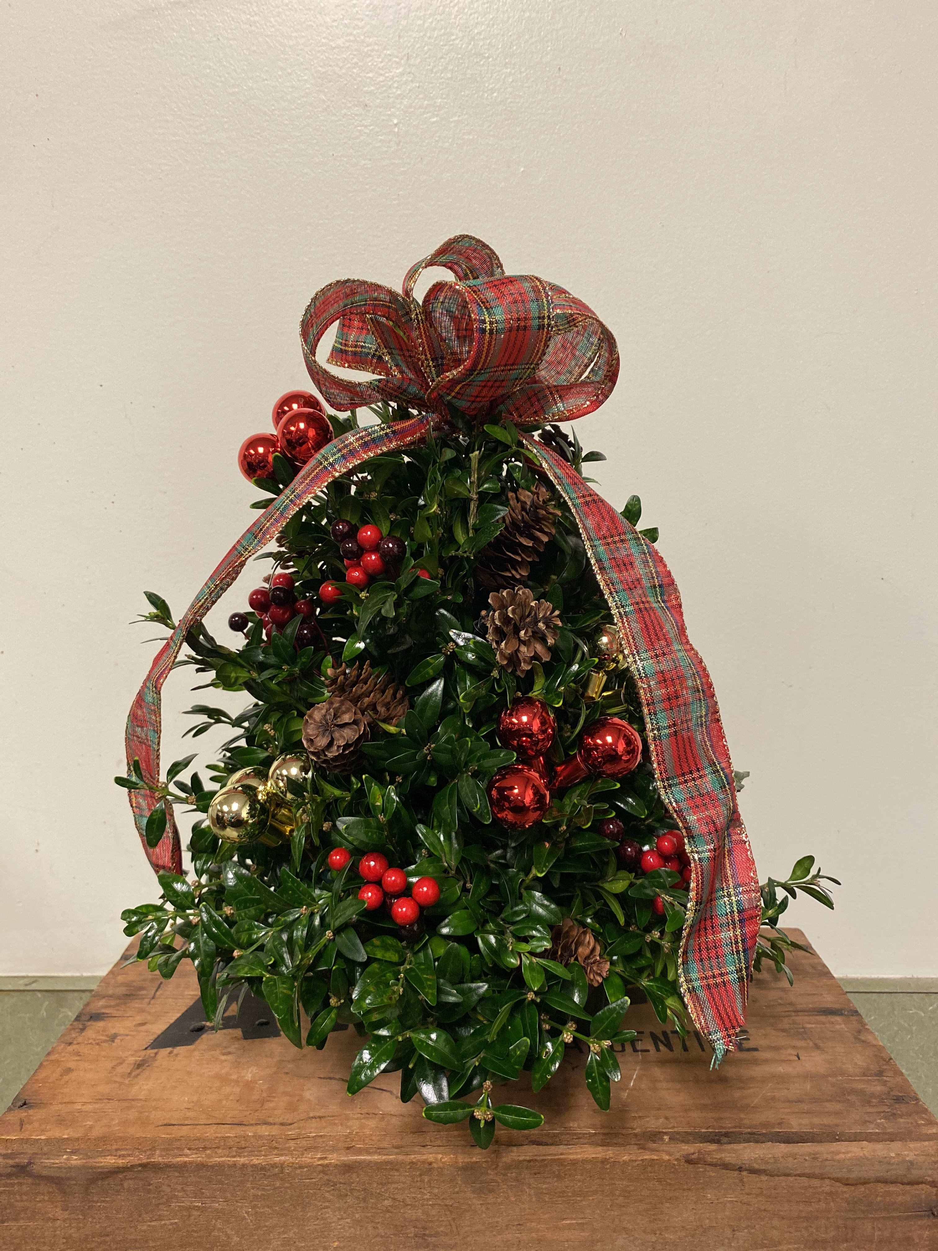 Small Boxwood Tree  - Celebrate the season with this sweet holiday tree hand-crafted of fresh cut boxwood. A gorgeous 15-inch tree arrives accented with natural cones and berries and seated in a sturdy, stable container.  A wonderful addition to the holiday decor.  Approximately 15 inches in height.