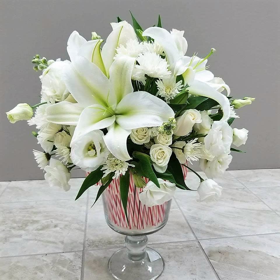 Winter Wonderland - A bouquet of mixed white flowers in a glass vase decorated with candy canes.