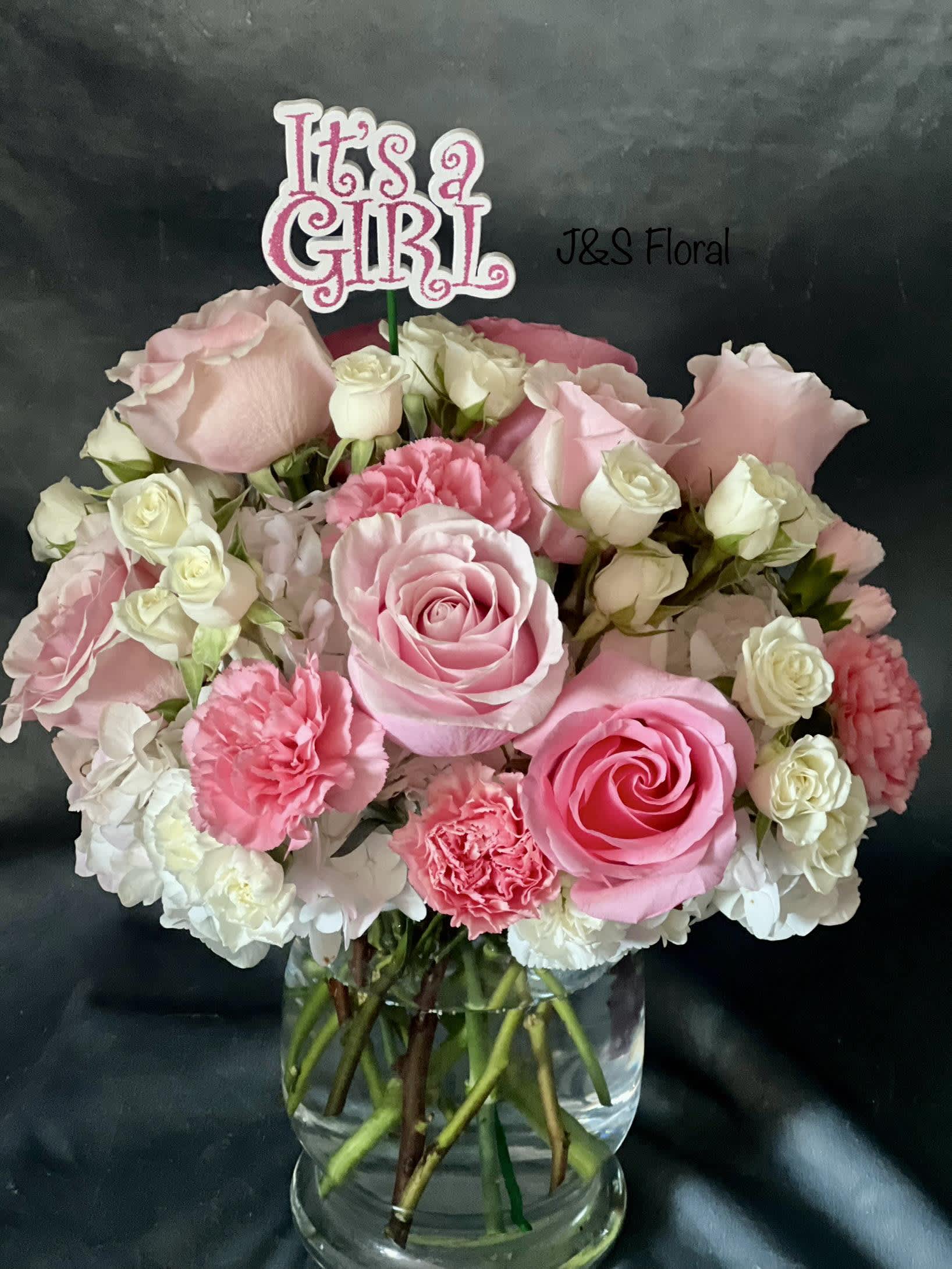 It's A Girl - Our Stunning It's A Girl Arrangement will definitely make their day!  The gorgeous arrangement with pink roses, pink carnation and white hydrangeas speak volumes! Beautifully hand made in a glass vase. The picture shows the standard size which is a beautiful way to say congratulation on your new bundle of Joy.