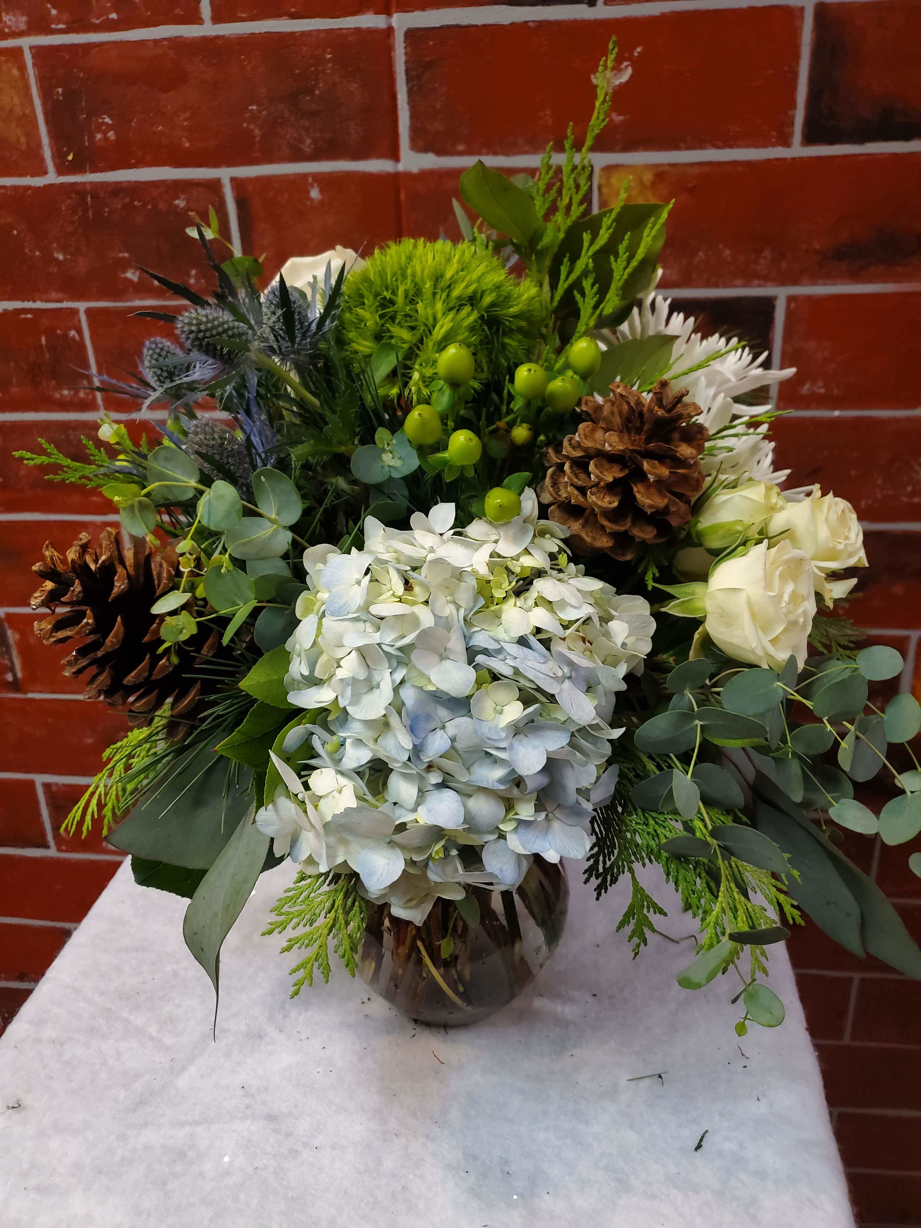 Winter Night  - This bouquet is all around designed with Pinecones, Thistle, hypericum, Hydrangea, spray roses and trix flowers.  * Some stages of flower life may vary. (Example: Lilies may be more open than imaged.)  Flower shortages and product availability means that some substitutions will apply. Value will always be filled.  This bouquet might include eucalyptus amongst the greenery. It may be toxic to pets including but not limited to Cats and Dogs if digested.