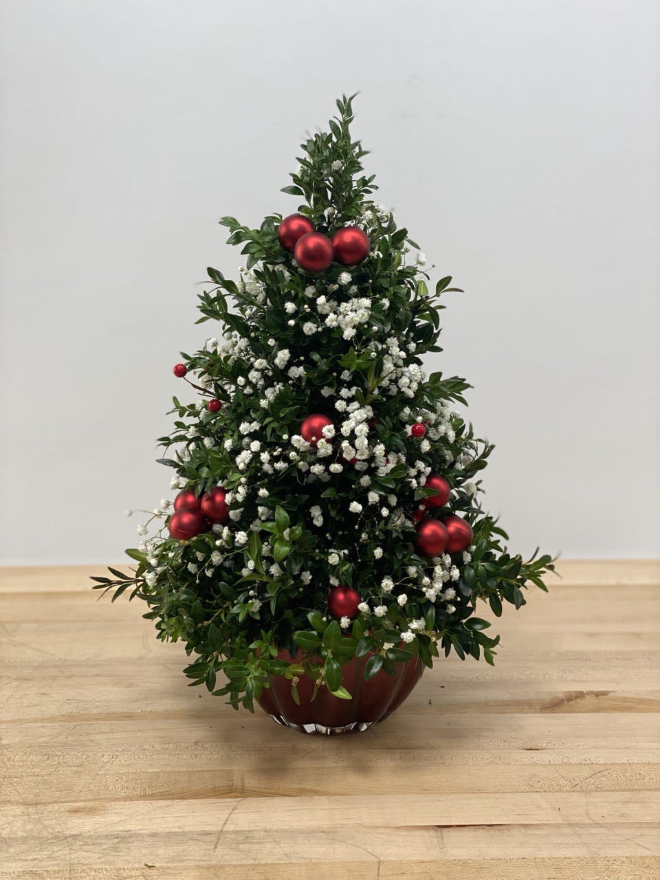 Mini joyful Tree - A cute mini boxwood Christmas tree decorated with baby's breath and red ornament balls, in a beautiful, high quality red glass container perfect as a gift or for your home décor. Dimensions: 19&quot; tall, 10&quot; wide