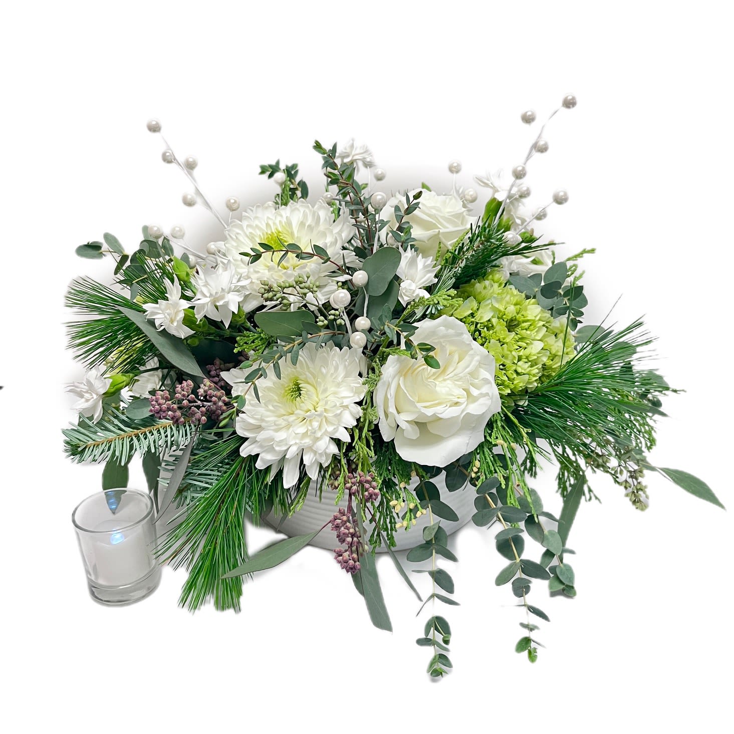 Snowberry - Add a frosty touch of whimsy to someone's holiday with Snowberry! This delightful arrangement combines snowy white mums, elegant Playa Blanca roses, mini green hydrangea, lush evergreen sprigs, and playful pearl-like snowberries that twinkle like winter magic. With cascading evergreen and soft eucalyptus accents, it’s a cheerful reminder of snowy days and cozy nights. Perfect for gifting or spreading joy, Snowberry is as fun and festive as a holiday snowball fight—minus the cold! Designed in a modern, white ceramic bowl.