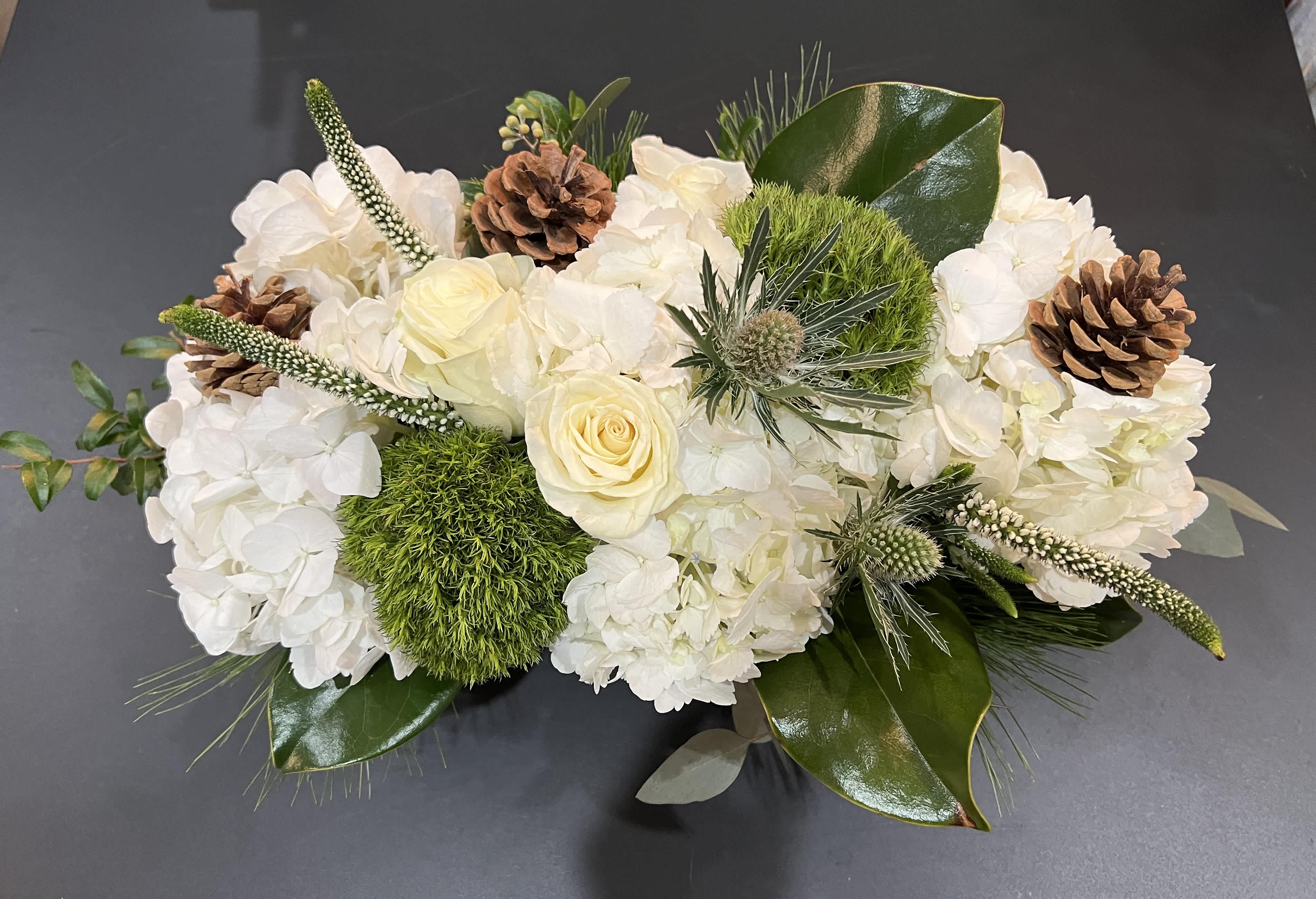 Frosty Fun - A perfect Christmas combo with roses, hydrangea, mixed seasonal greens and pine cones.  Delivery minimum is $50.00 Our DELIVERY SERVICE IS TILL 3 PM We cannot guarantee requests for a specific time of delivery. There might be flower substitutions, due to low supply of certain flowers. However, we do our best to provide you with the same look and feel of the arrangement. Our main goal is to always give our customers quality flowers and service. To make sure that you get the exact same flowers, ordering a few days ahead of desired delivery date is key.