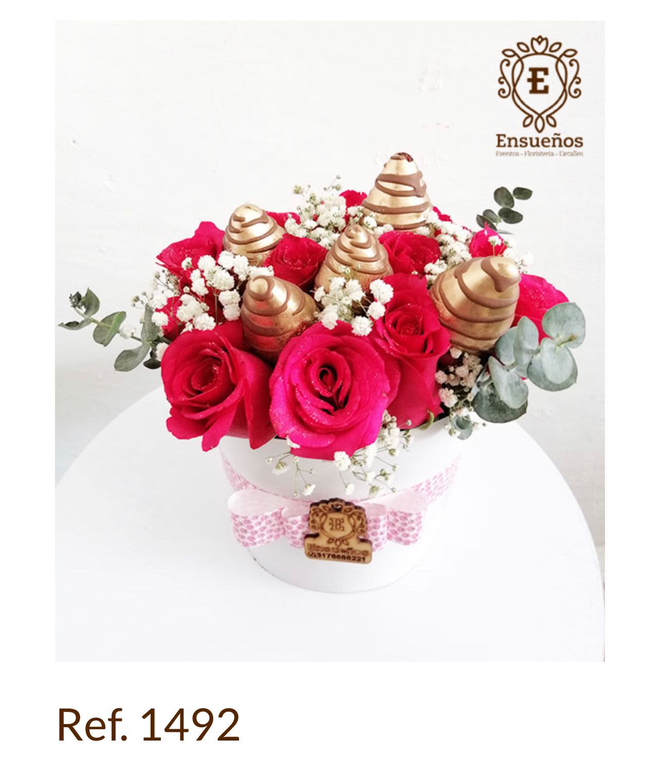Caja Rosas Glam Gold - La Caja Rosas Glam Gold es un diseño sofisticado y llamativo, ideal para quienes buscan un detalle con elegancia y brillo. Está elaborada con rosas fucsias premium, acompañadas de gypso blanco y toque verde de eucalyptus para equilibrar la composición.  El elemento protagonista son los conos decorativos dorados, que aportan un estilo glamuroso y diferente, convirtiendo este arreglo en un regalo exclusivo y moderno.  La base es una caja blanca decorada con cinta rosada, que complementa la armonía del color y crea una presentación perfecta para cualquier ocasión especial.ste diseño SIEMPRE requiere un mínimo de 10 días de anticipación, ya que se elabora únicamente bajo pedido y contiene elementos decorativos especiales.
