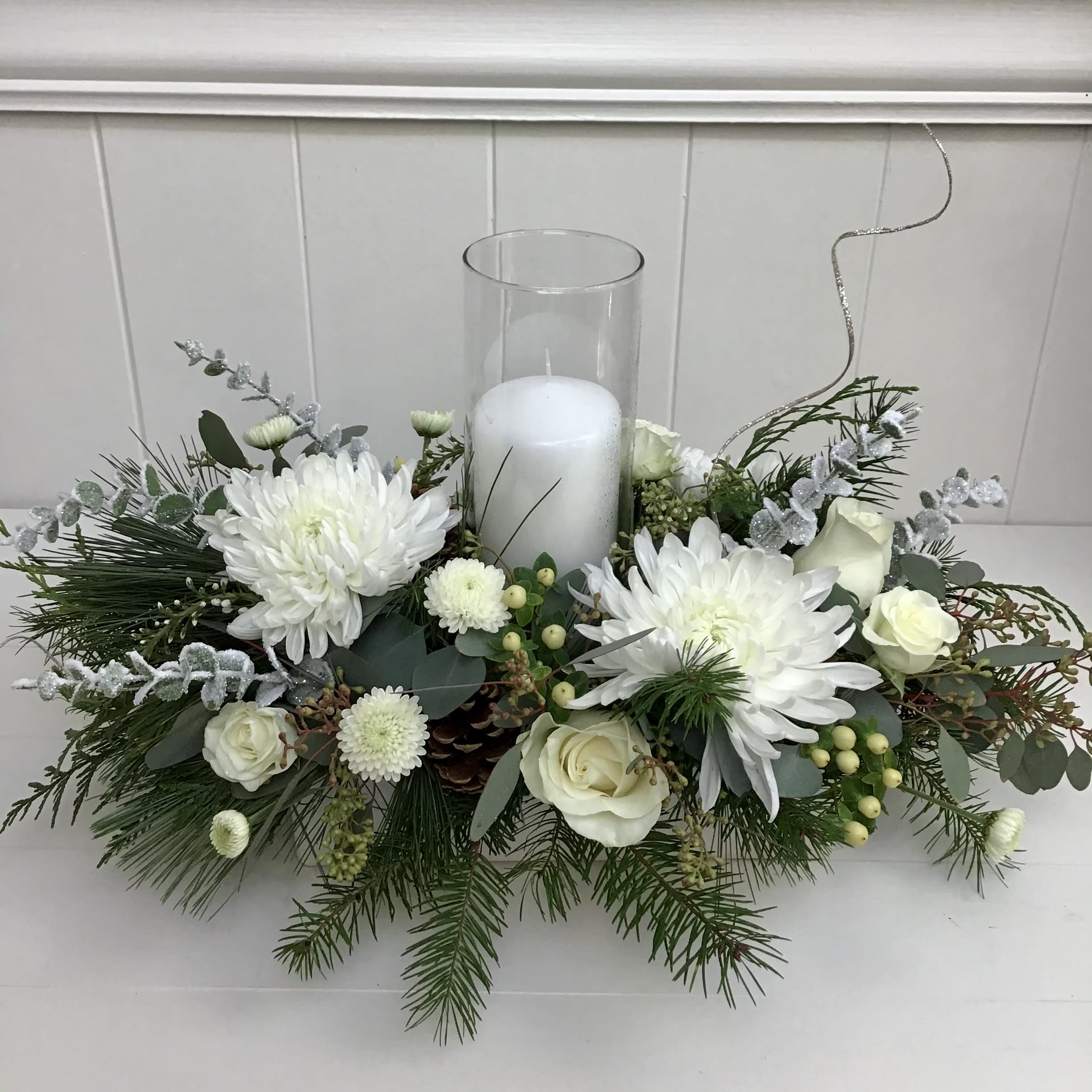 Winter Wonderland - A Christmas centerpiece with all white flowers and natural Christmas greenery. Decorated with festive ornamentals to bring a shimmery arrangement into the home!