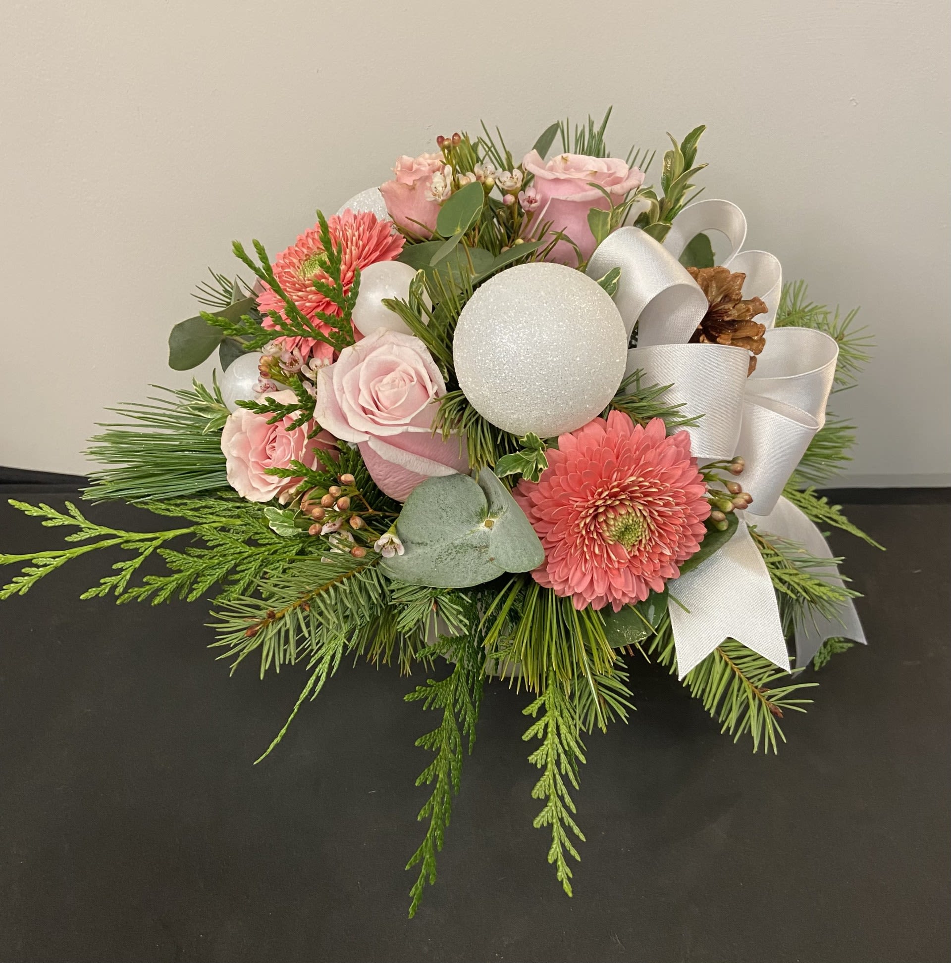 Winter Rose by Chasing Petals - Winter Rose captures the soft beauty of the season with delicate pink blooms, frosted accents, and lush evergreens. Styled with elegant winter textures and a touch of sparkle, this graceful arrangement brings a serene, romantic glow to any holiday setting. Perfect for gifting or adding a refined touch to your own winter décor.