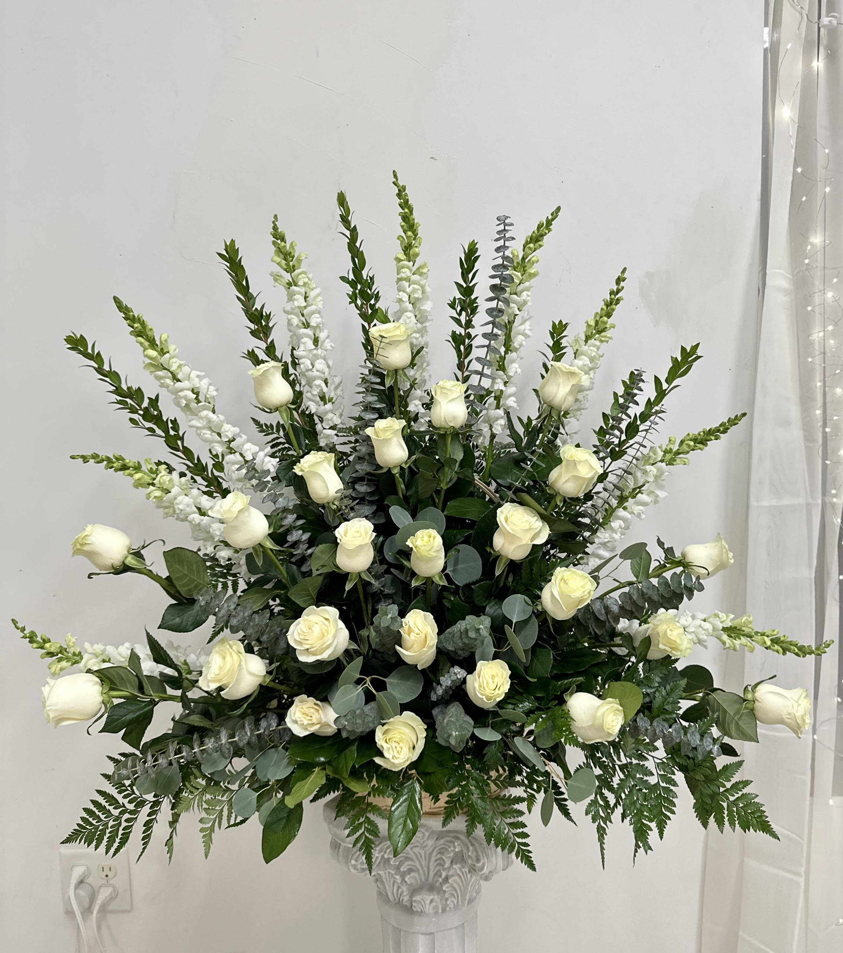 Heavenly Light by Westford Florist Art by Veny - In moments of loss, finding a beautiful way to honor your cherished memories can bring solace amidst the sorrow. The Heavenly Light Sympathy One Sided Arrangement by Westford Florist Art by Veny is thoughtfully designed to provide comfort and grace during such emotional times. This exquisite one-sided arrangement showcases two dozen pristine white roses, symbolizing purity and remembrance, elegantly complemented by seasonal blooms that enhance its beauty. With each bloom meticulously chosen, this tribute becomes not just an expression of sympathy but a heartfelt reflection of love and respect for the departed. Allow the Heavenly Light arrangement to convey your deepest condolences and celebrate their lasting legacy with elegance and compassion. Let the Heavenly Light Sympathy Arrangement by Westford Florist serve as a comforting reminder of cherished memories shared with your departed loved one. Pay tribute in style with this exquisite arrangement that speaks volumes without saying a word – conveying all you wish you could say through carefully chosen flowers. The Heavenly Light Sympathy Arrangement by Westford Florist offers a touching and heartfelt way to honor the memory of a dear friend or loved one. Its elegant design and symbolic flowers make it a beautiful addition to any service or setting. Let this arrangement serve as a reminder of the love and cherished memories that will always be held close in your heart.