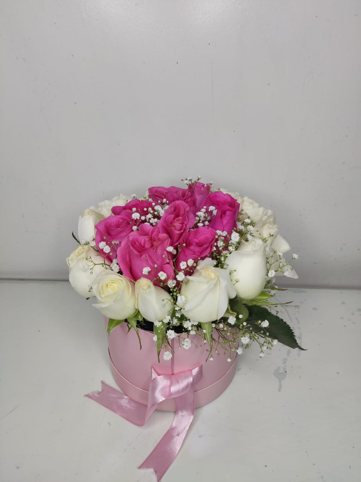 Caja Rosas Duo Pink - La Caja Rosas Duo Pink es un diseño delicado, femenino y lleno de encanto. Está elaborado con una hermosa combinación de rosas blancas y rosas fucsias, creando un contraste elegante y muy llamativo. El toque de gypso blanco aporta suavidad y un acabado romántico.  El arreglo viene presentado en una caja redonda rosada, adornada con un moño satinado que realza la ternura del diseño. Es un detalle perfecto para regalar en ocasiones especiales o simplemente para sorprender con algo hermoso y de calidad.Este diseño SIEMPRE requiere un mínimo de 10 días de antelación, ya que se realiza sólo por encargo y contiene elementos decorativos especiales.