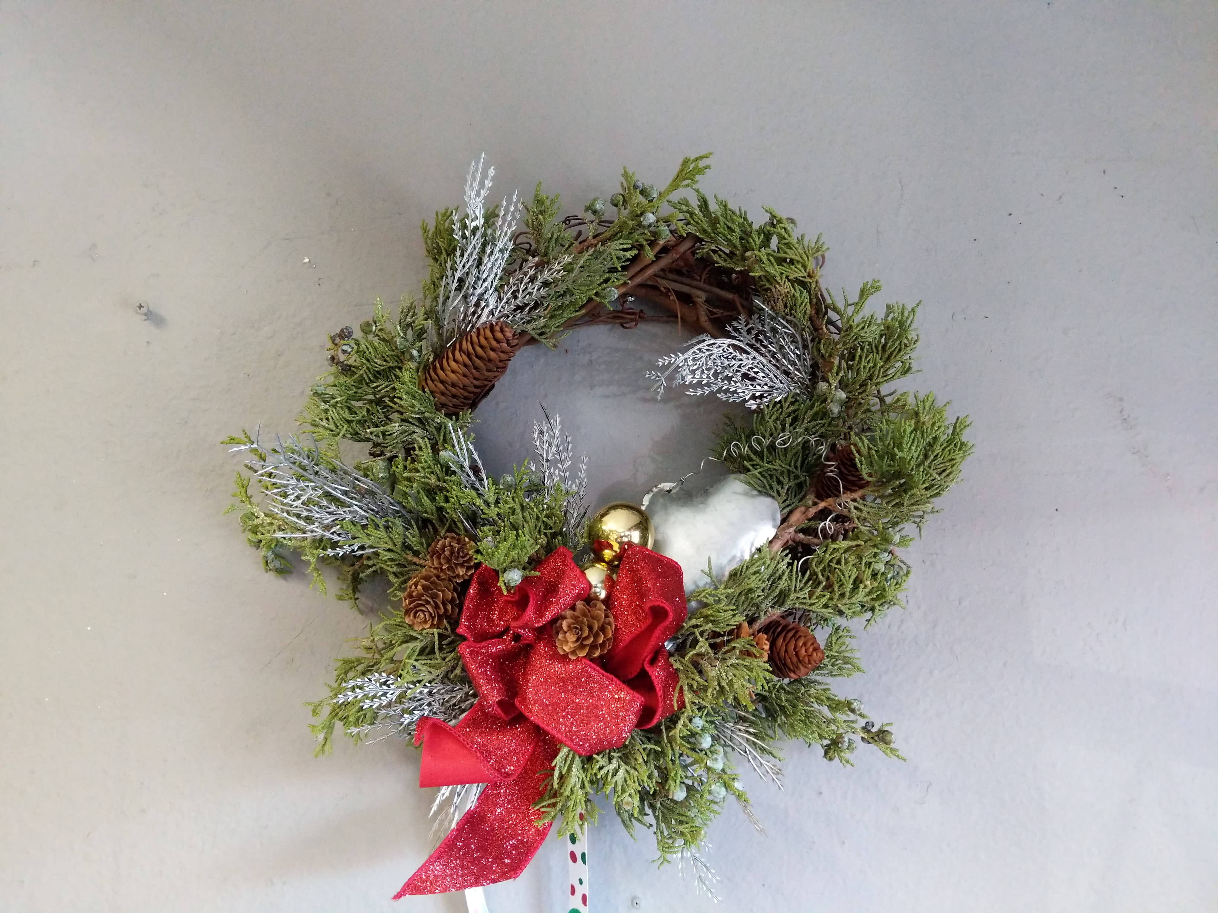 Festive Holiday Wreath  - This magical wreath is made with holiday greenery and silver accents. Everything is tied up with a cute red bow and silver star