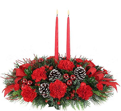 Joy to the World -  Classic centrepiece arrangement with a red taper candle, featuring long-lasting red carnations and miniature carnations with abundant Christmas greenery, red berries and red ribbon.