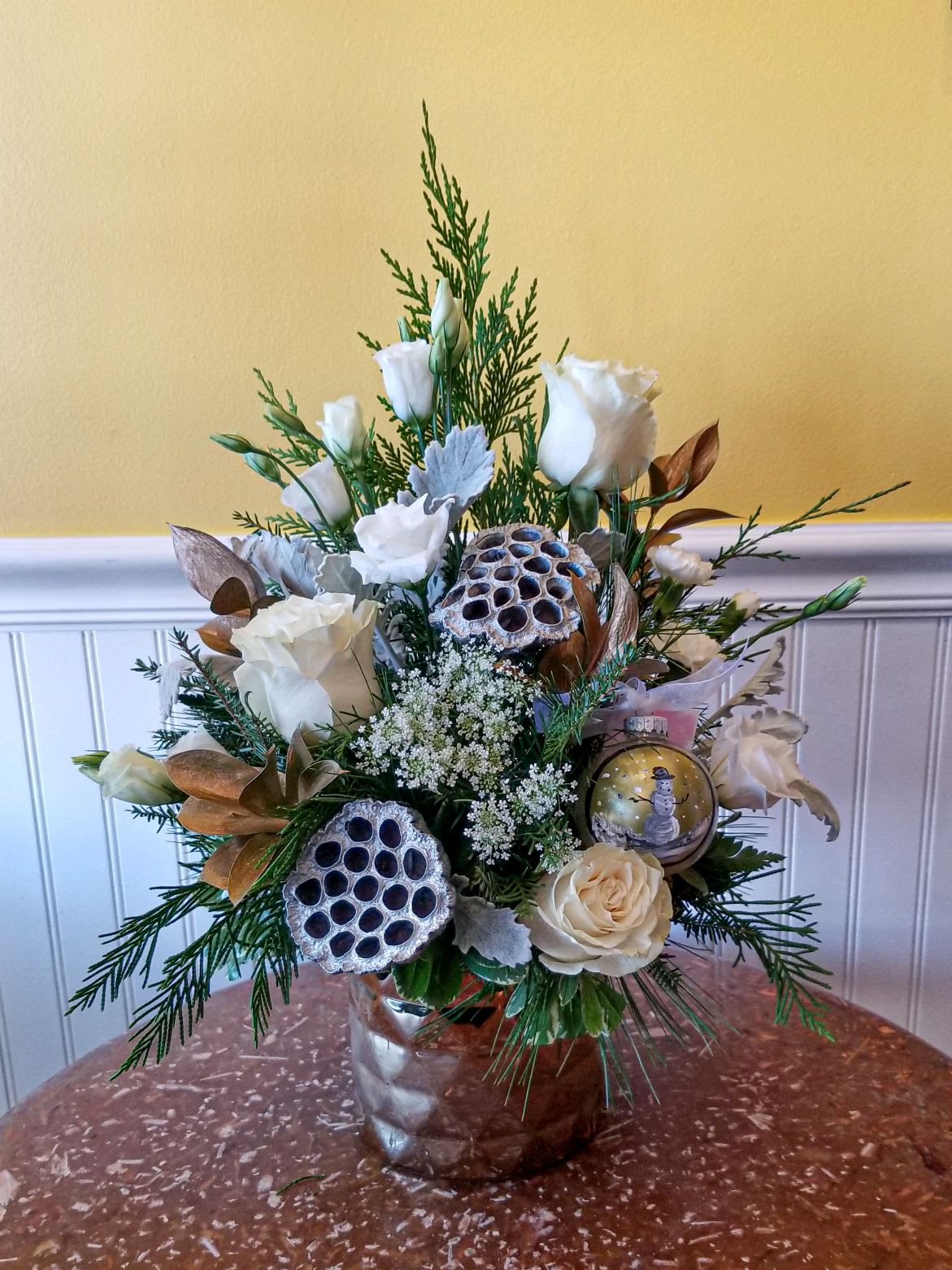 Painted Expressions - X Mas Edition - Looking for that something special ? We have teamed up with a local artist Stefanie Snapp, to include some of her exquisite , one of a kind, hand painted pieces. All art pieces are unique, and thus may not be exactly as pictured, however they are all similar themes. The hand painted piece is on a glass ornament. This floral arrangement is designed in a gold ceramic cylinder. ***Please note, upgrading this design will increase the number of blooms, not the size of the ornament. *** Dimensions: 20x15 If you would like to see more of Stefanie's artwork, please visit her website https://www.arttoappreciate.gallery/