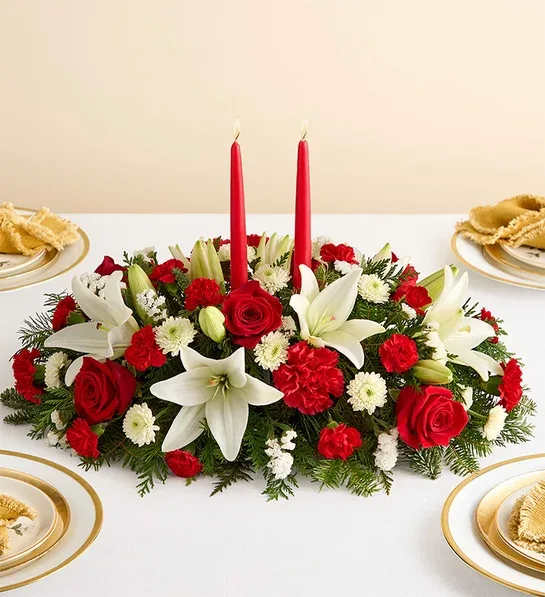 Traditional Christmas Centerpiece  - Our classic table arrangement is an idyllic centerpiece for your Christmas celebration. Beautifully designed with long-lasting blooms in seasonal colors, this fragrant gathering features red taper candles to cast a warm, inviting glow throughout the holidays.