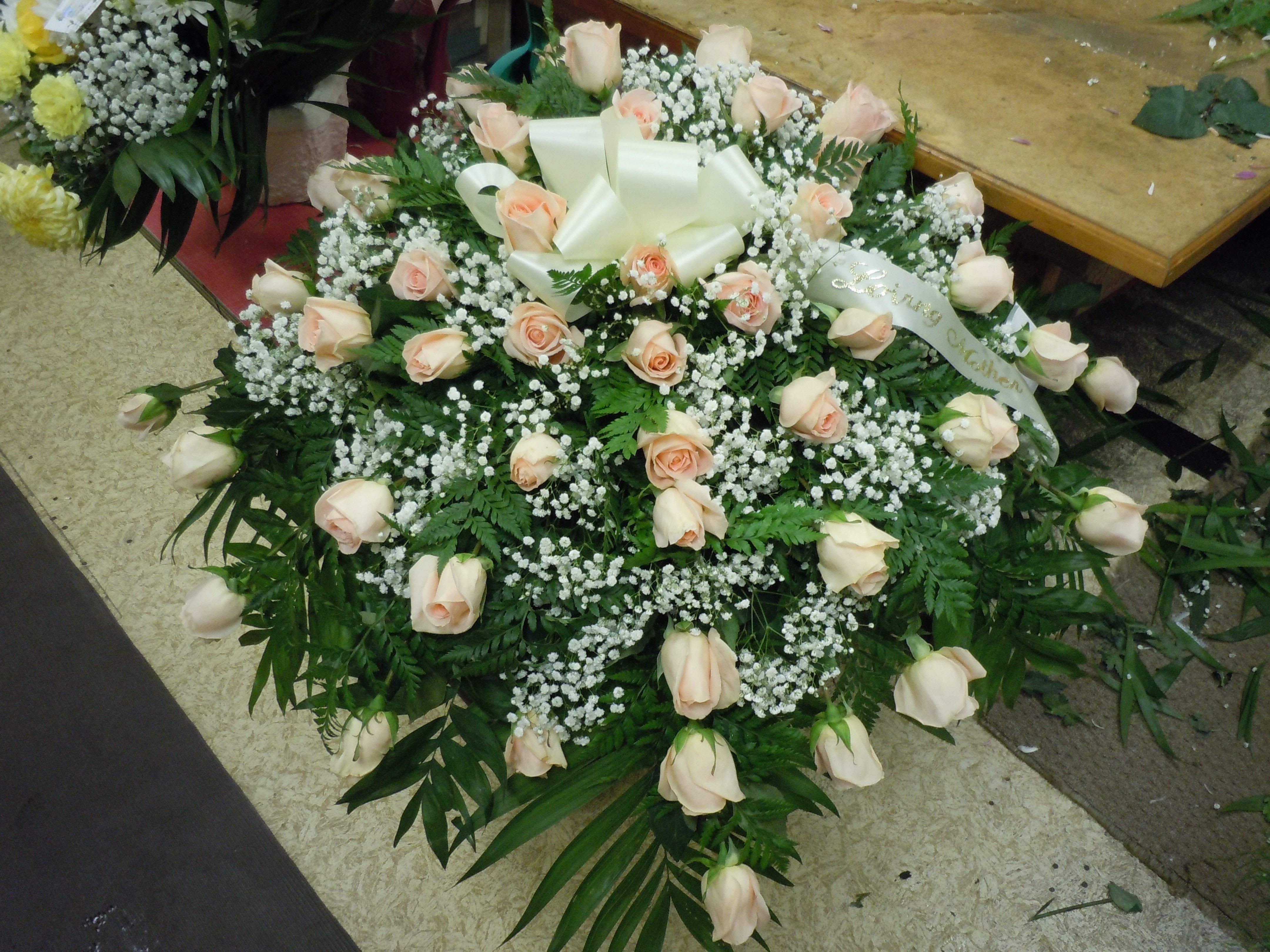 C17 Casket Spray - Peach roses,  greens, and baby's breath.   Banner - $15.00 + extra  Substitutions may apply, pending flower availability.