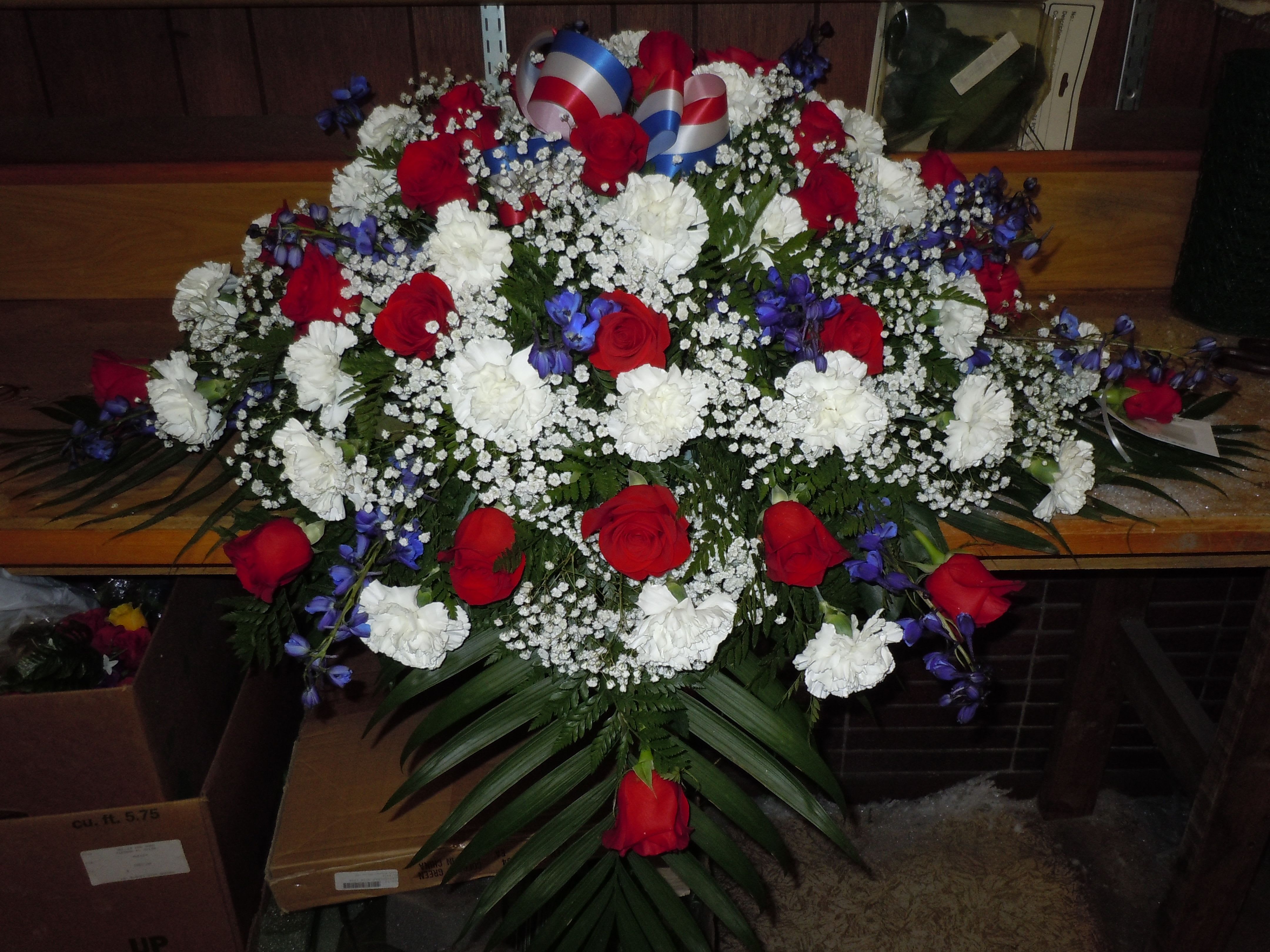 C21 Casket Spray - Red, white and blue casket spray includes bow.  Banner - $15.00 + extra  Substitutions may apply due to flower availability      