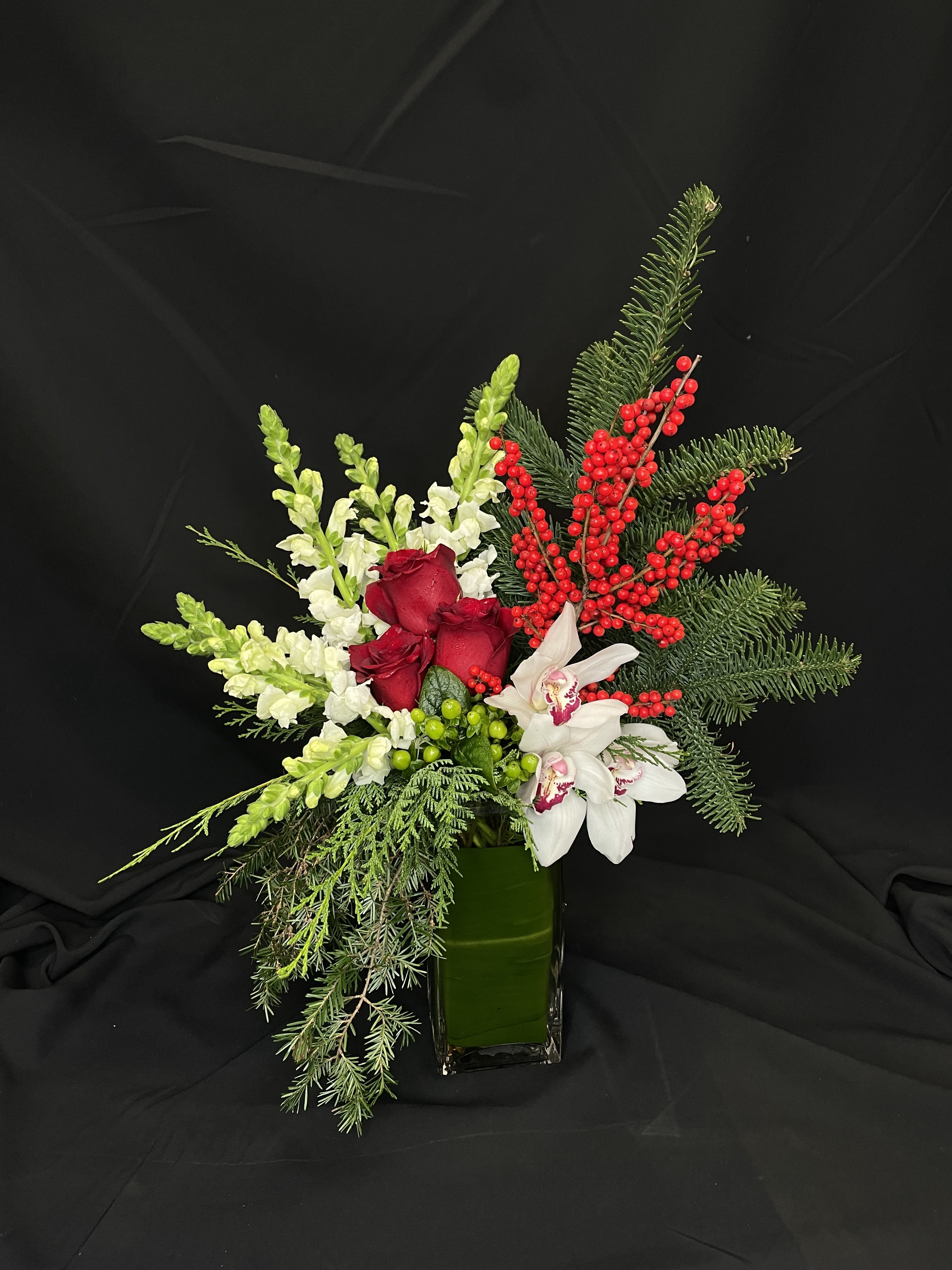 Orchids on the Bough - For lovers of our popular fall arrangement &quot;Orchid Harvest,&quot; we made Orchids on the Bough. A festive tall asymmetrical bouquet featuring white cymbidiums, ilex berries, pine, snapdragons, and roses. This holiday arrangement brightens up every room with its bold style and colors.