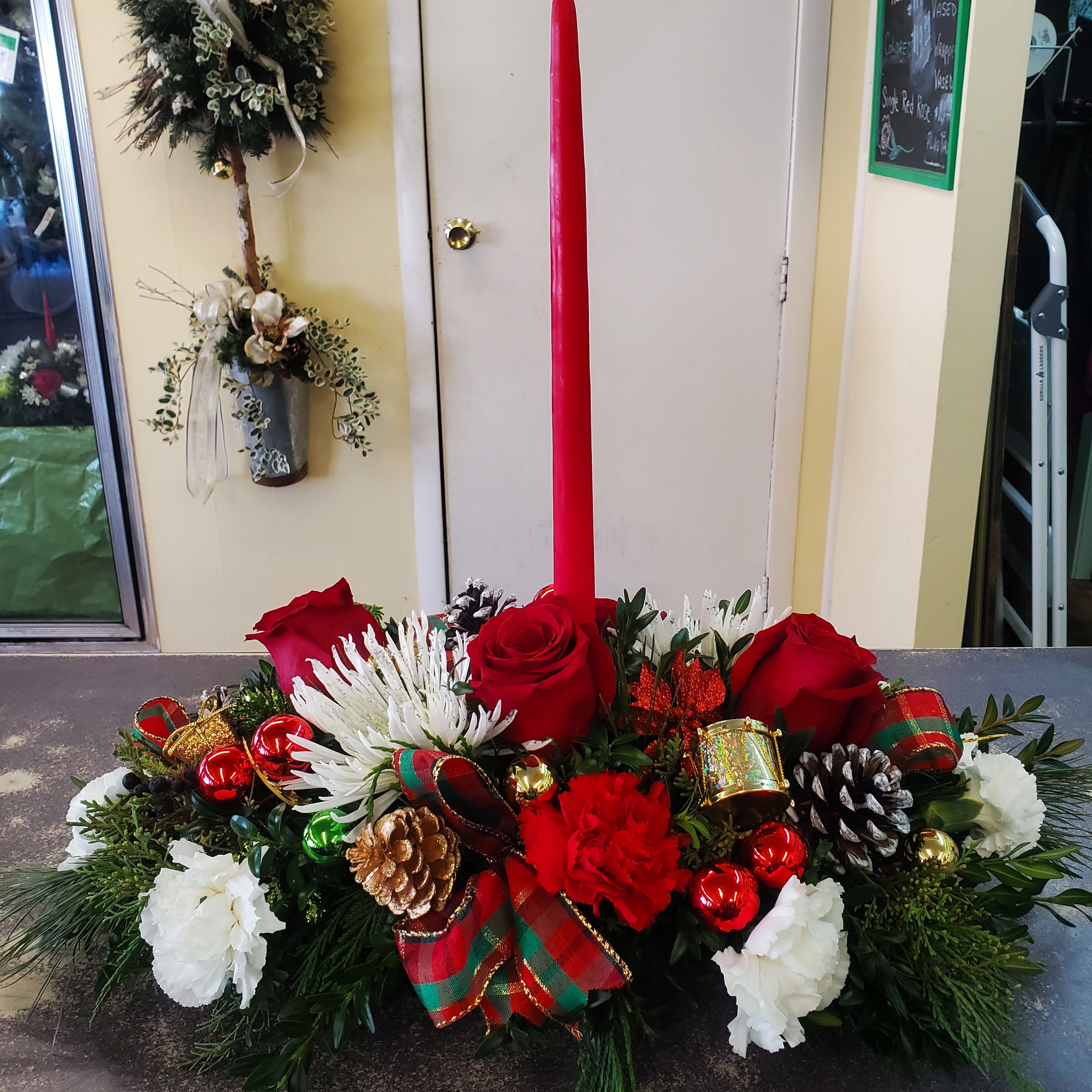 Festive Table Arrangement  - Traditional table centerpiece with tall tapper candles. Assorted winter greens red and white flowers.  **PLEASE NOTE..COLORS AND FLOWERS WILL VARY DEPENDING ON THE AVAILABILITY OF THE DAY **
