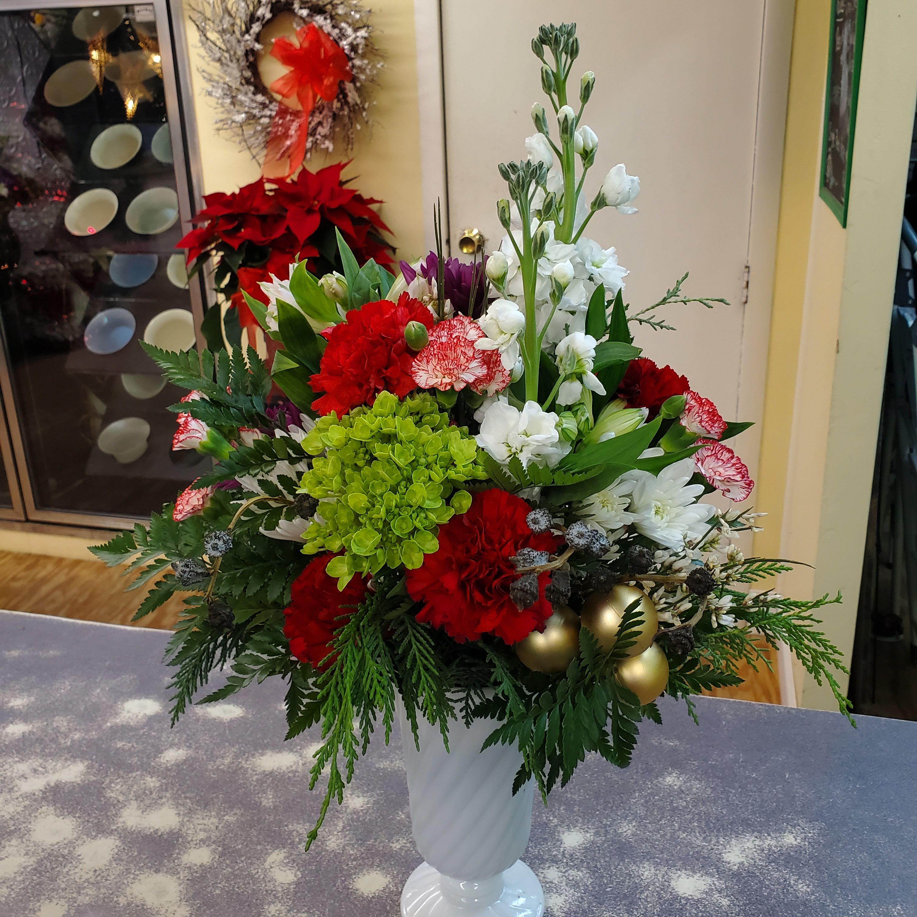 Jingle Bell Bouquet  - A glass vase filled with assorted seasonal winter greens and flowers.  A festive holiday bouquet. 