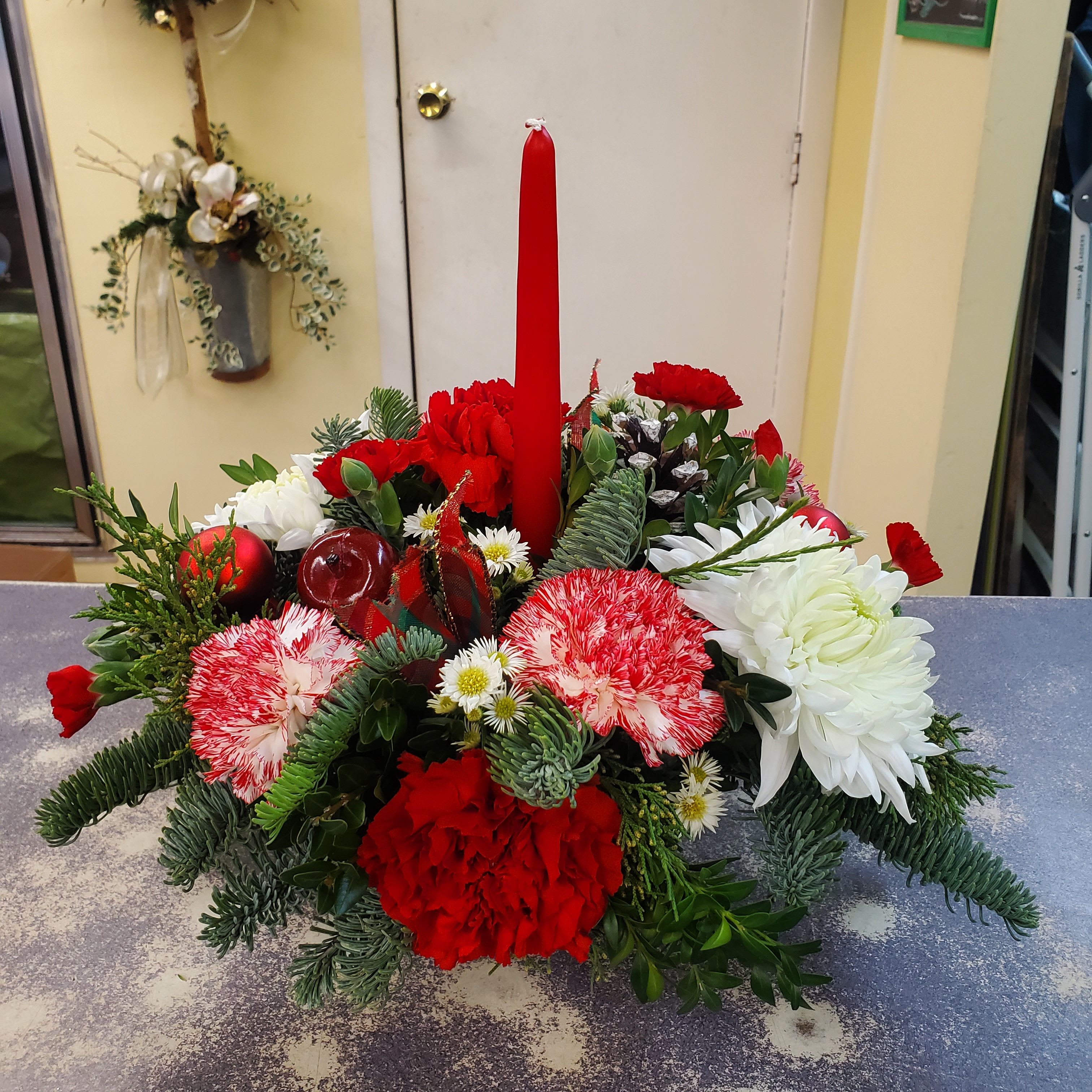 Round Christmas Table Arrangement  - Round table arrangement filled with assorted winter greens and seasonal flowers with candle.  **COLORS WILL VARY DEPENDING ON THE AVAILABILITY OF THE DAY **