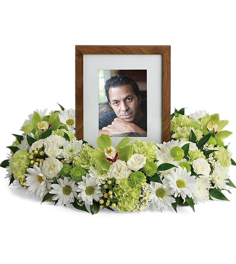 Garden Wreath Photo Tribute  - An exquisite round wreath with blooms inspired by the lasting impressions a loved one makes on our lives. Surround a treasured photograph, poem or other dear memento with sweet, green carnations, white and green chrysanthemums and the special beauty of green cymbidium orchids. This luxurious wreath includes flowers such as carnations, chrysanthemums, silky green cymbidium orchid blossoms and variegated greenery. Please note: Arrangement does not include picture frame. Approximately 21" W x 15" H