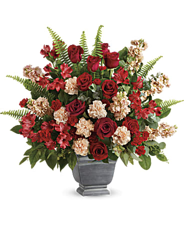 Teleflora's Bold Tribute Bouquet - DESCRIPTION VASE SIZES Bold and beautiful, this majestic mix of red roses and fresh greens in a large, stone-inspired pot is a show of strength and support. Red roses, red alstroemeria, peach carnations, miniature red carnations, and peach stock are arranged with spiral eucalyptus, seeded eucalyptus, sword fern, and lemon leaf. Delivered in Teleflora's Modern Heritage pot. Orientation: One-Sided  SUBSTITUTION POLICY – Always deliver the freshest flowers! Please note the bouquet pictured reflects our original design.  If the exact flowers or container in this arrangement are not available, our local florists will create a beautiful bouquet with the freshest available flowers.