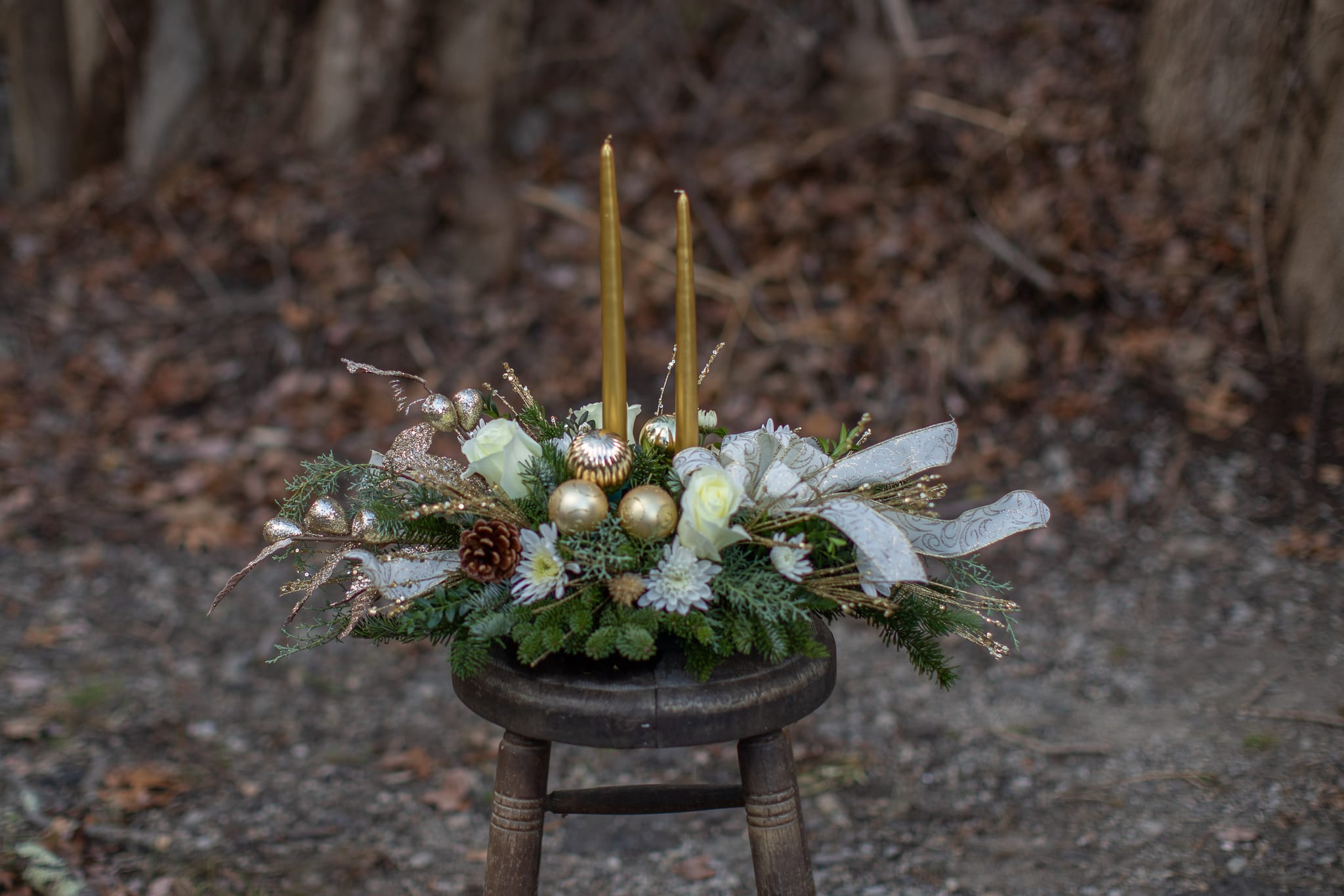 Golden Glow  Centerpiece - Know someone who deserves the royal treatment this holiday season? This shimmering golden centerpiece will shine its golden light upon them. Gorgeous gold taper candles take center stage in an arrangement of crème roses and gold ornaments pinecones intricate designer ribbon Christmas greenery and more. This kind of high style really is fit for a king or queen! Available with out candles also, please specify in special instructions.