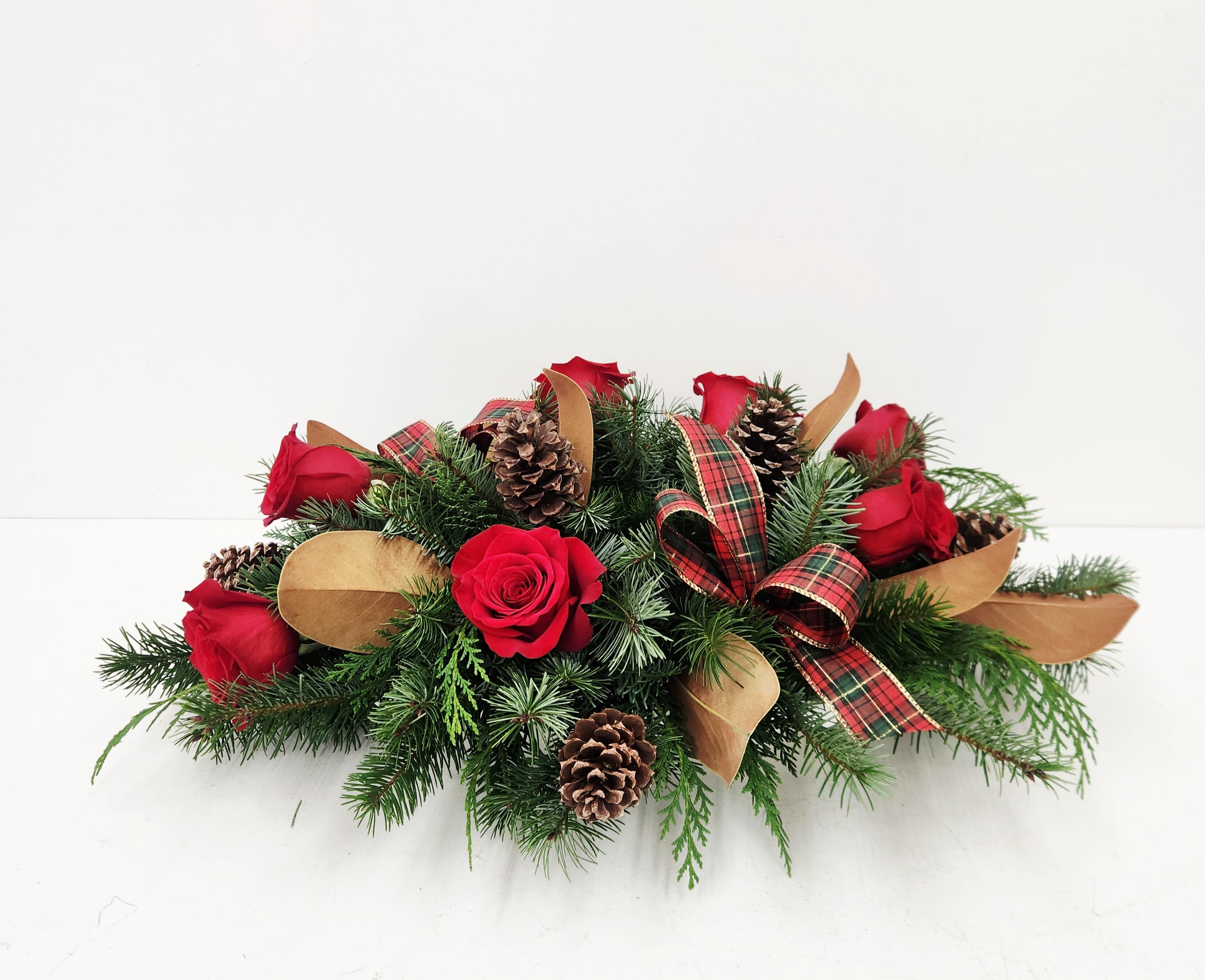 Vintage Christmas Centerpiece - Elevate your holiday décor with this timeless centerpiece, thoughtfully composed with deep red roses, lush magnolia leaves, and natural pinecones. Finished with elegant plaid bows, this arrangement captures the essence of refined seasonal elegance. Perfect for dining tables, mantels, or entryways, it brings warmth and sophistication to any space throughout the festive season.