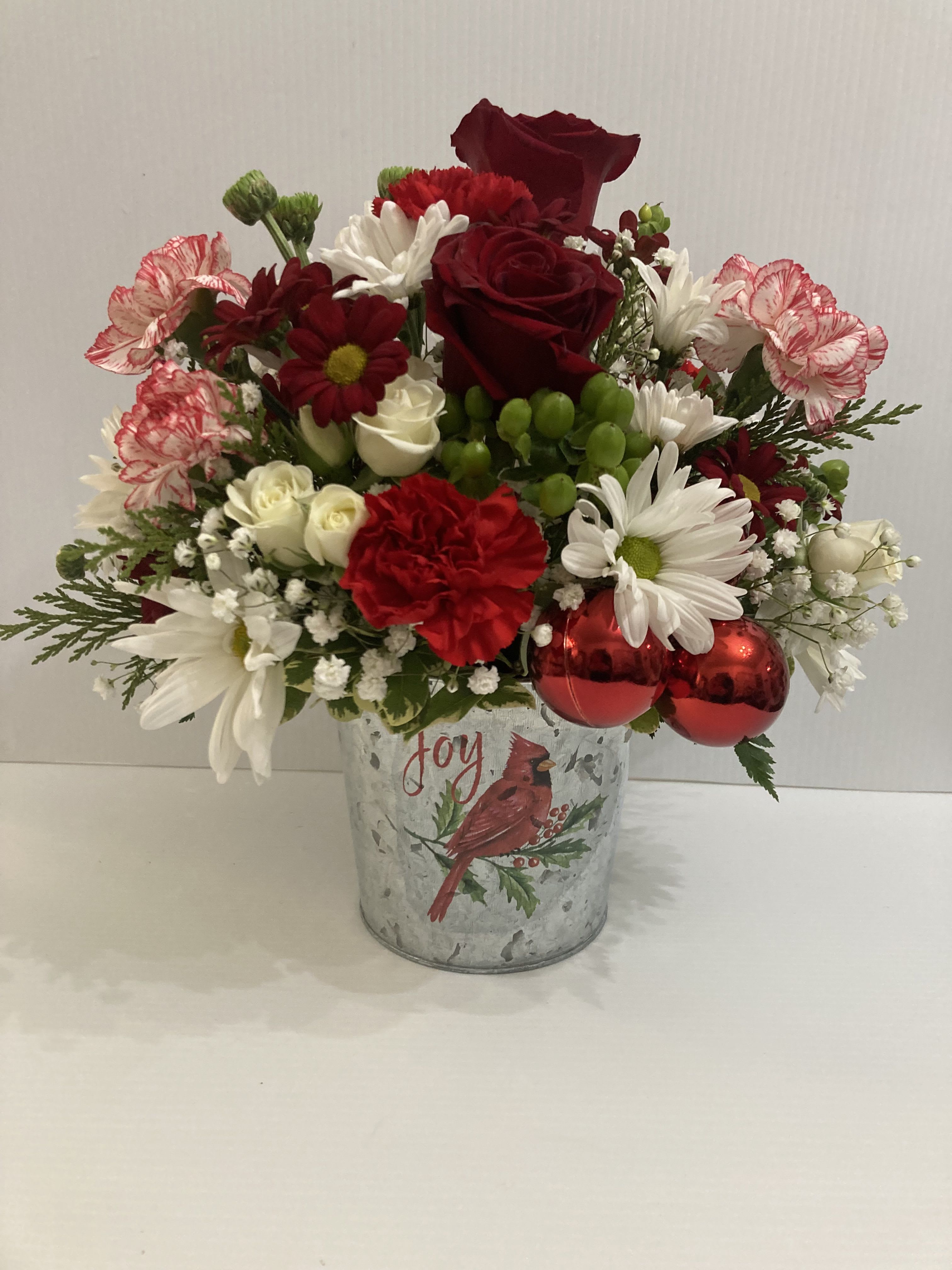 Christmas Joy - Exquisite arrangement with in a beautiful cardinal designers pot with roses, carnations, daisies, berries, cedar, and button moms