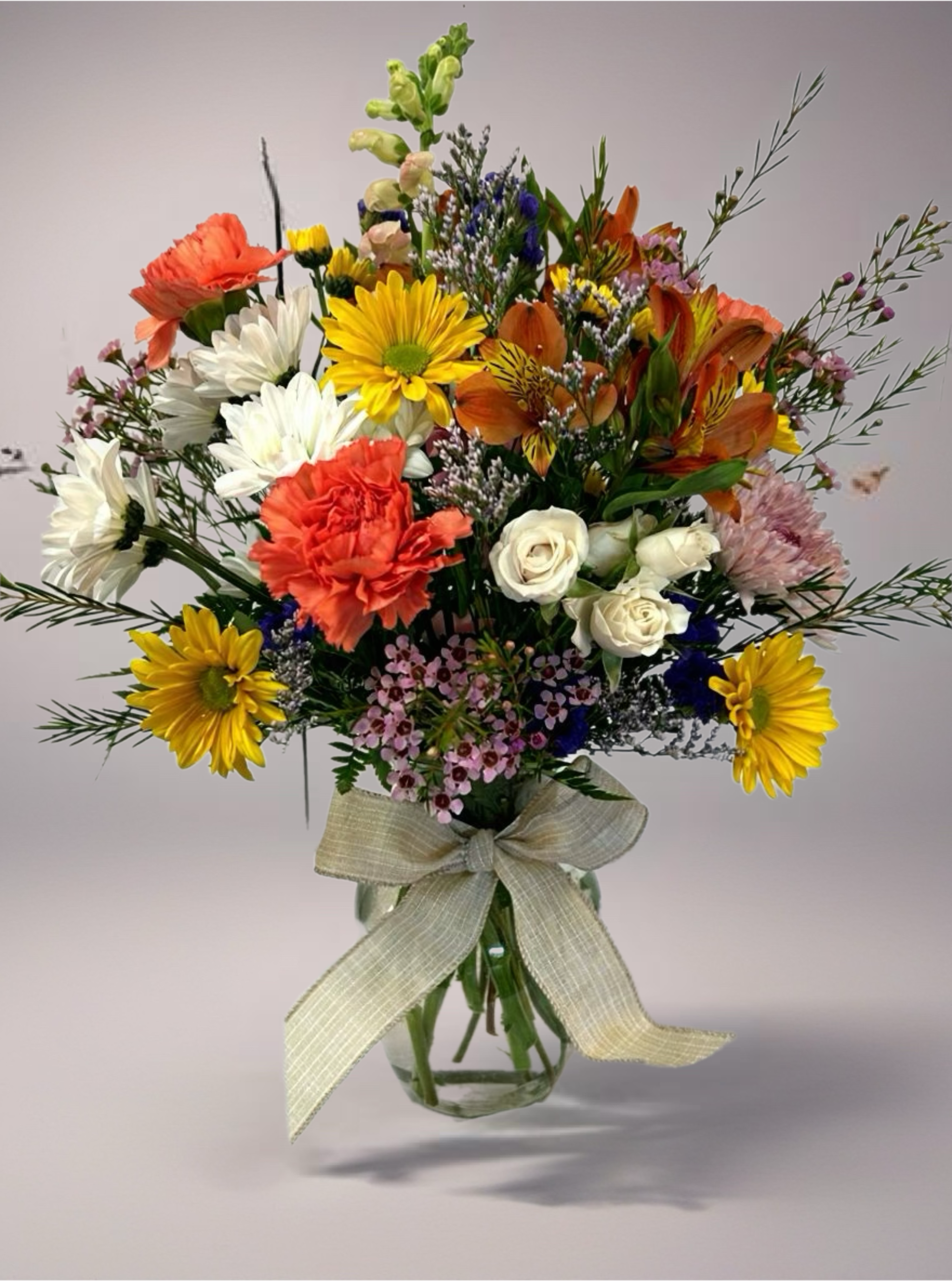 Girl Next Door - No fuss or muss just plain beautiful.  This arrangement is full of color and a variety of classic favorites.  Medium sized in a clear vase, the Girl Next Door is the perfect fit for any occasion.  ***Flower types depend on availability and season.  Size and style will match but colors and flower types may be different than photo.***