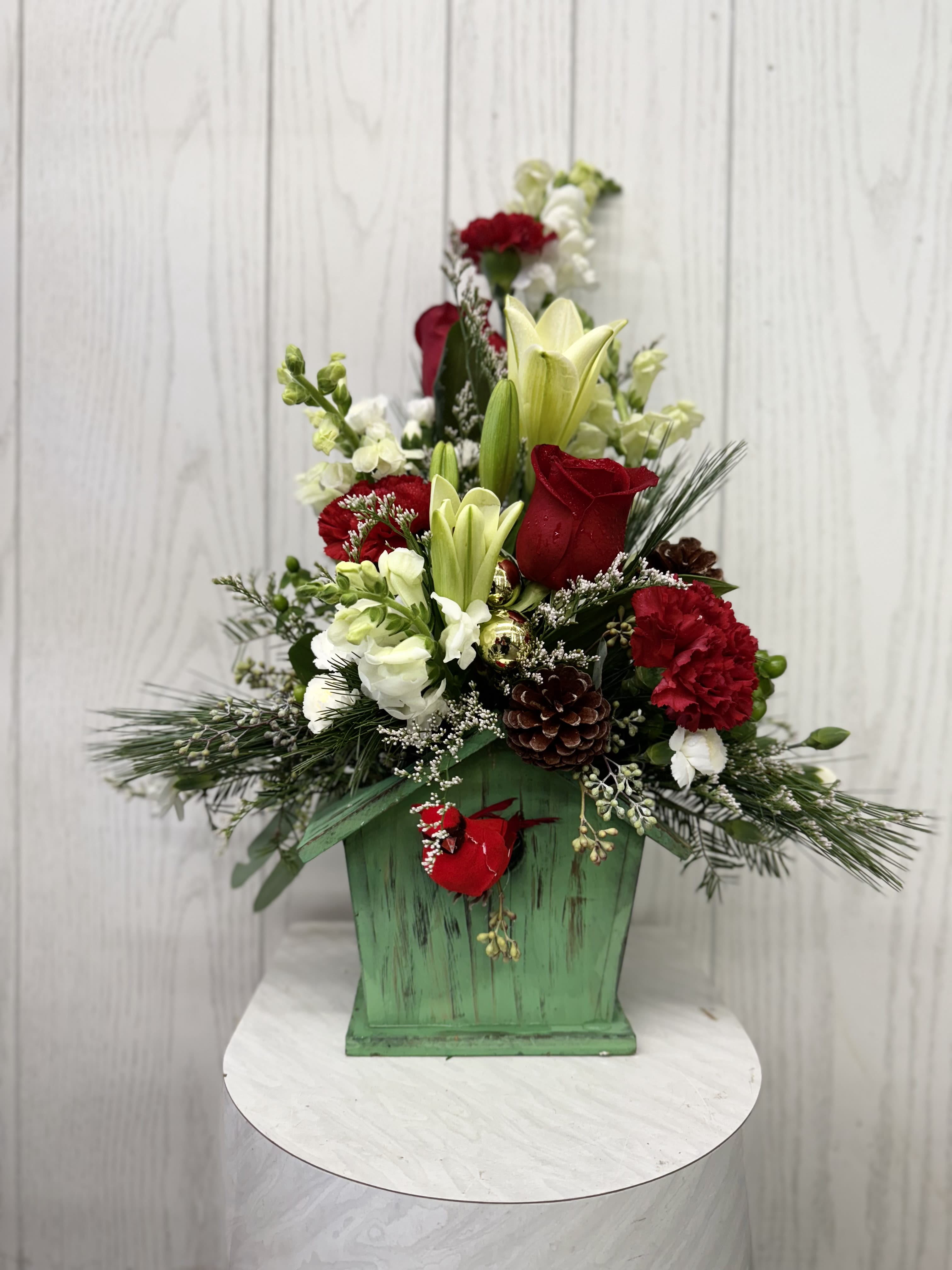 Holiday Birdhouse Arrangement - This festive birdbouse is adorned with traditional flowers, seasonal colors, and a red cardinal. Arrangement is approximately 17 inches high. Deluxe and premium include more flowers.  Substitution of flowers may be necessary based on the current floral inventory. The overall look, feel, and value will be maintained.  