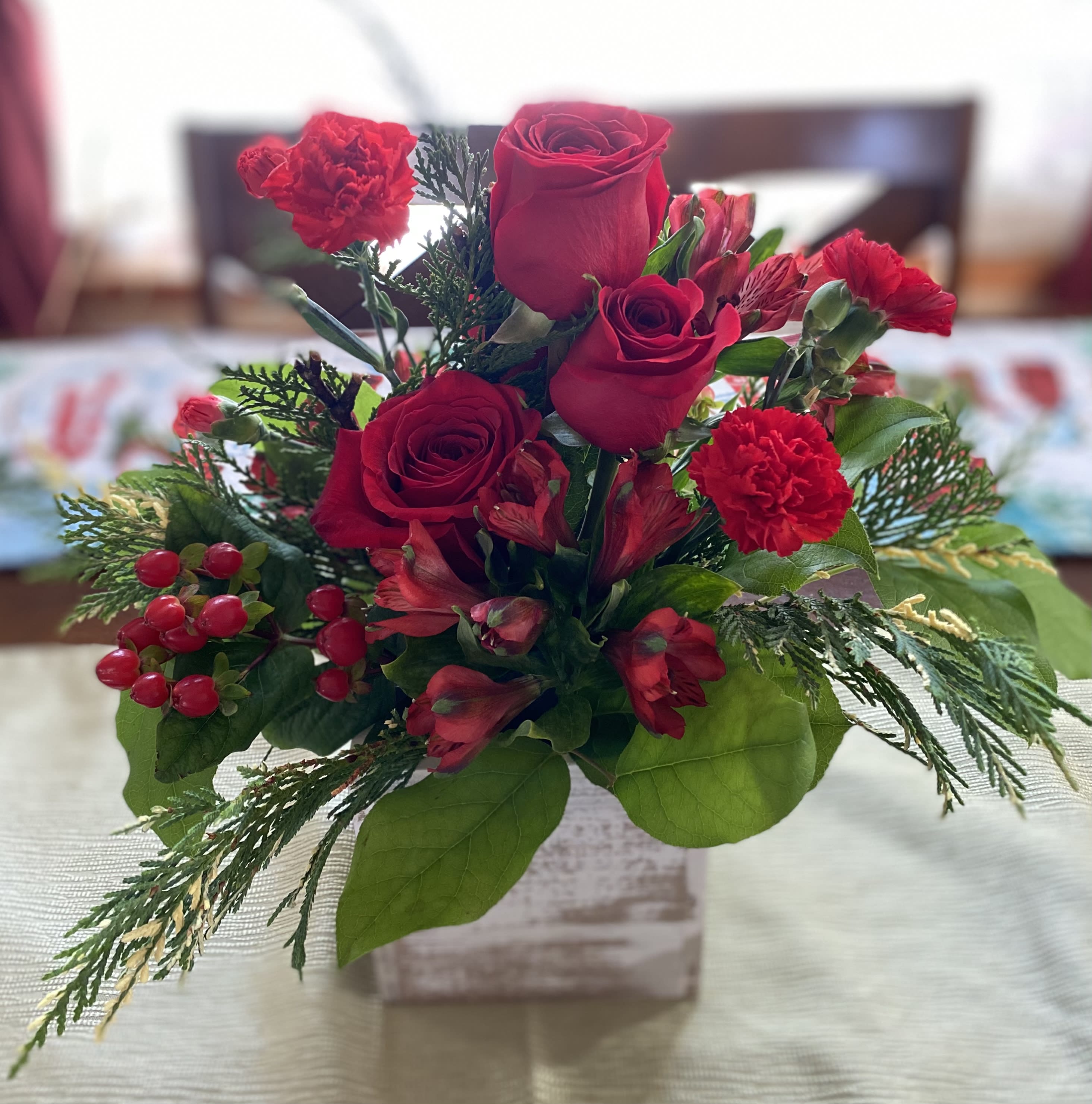 Reason for The Season - This trio of red roses is surrounded by red berries, alstroemerias and carnations with fragrant pine and greenery in a white washed wood box. Bless someone with this lovely reminder of the reason for the season today. 