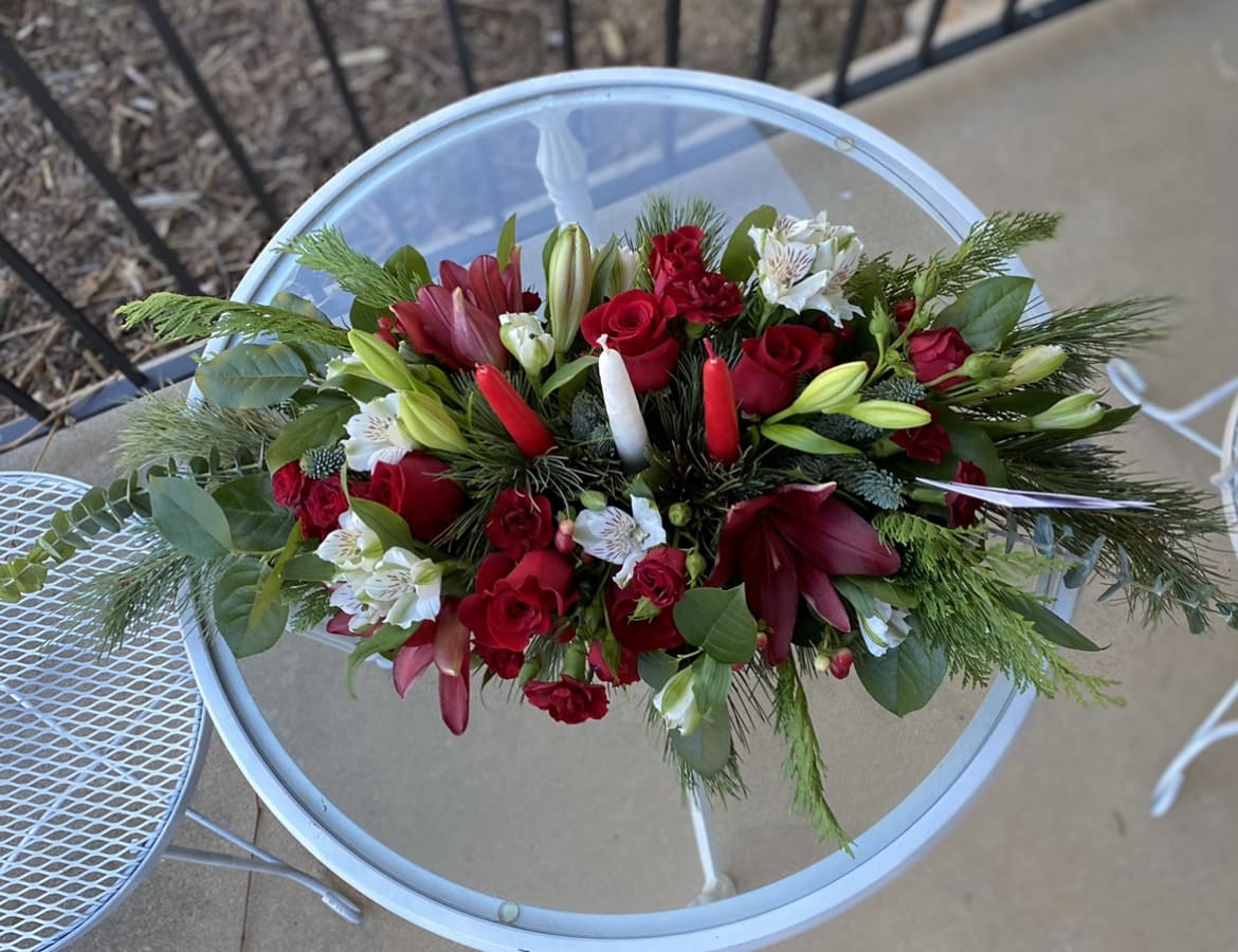 Colors of Christmas Centerpiece - Red, and white flowers in lush Christmas greens make up this lovely centerpiece. Whether you are having a quiet Christmas Dinner with your honey or a large gathering, our Colors of Christmas Centerpiece is the perfect addition to your dinner table.   May have white lilies and red alstroemerias depending on availability. 
