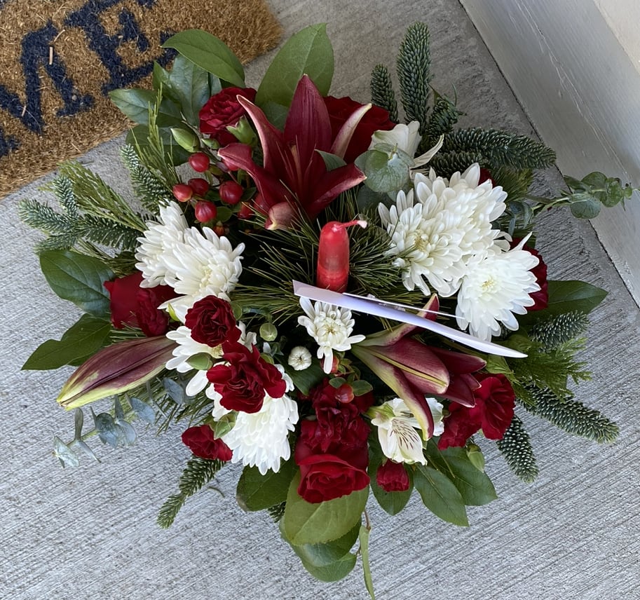 Christmas Cheer - Send a little Christmas Cheer when you can’t be there to celebrate the holidays with friends and loved ones.   10” round centerpiece with candle. Lilies may be white due to availability. 