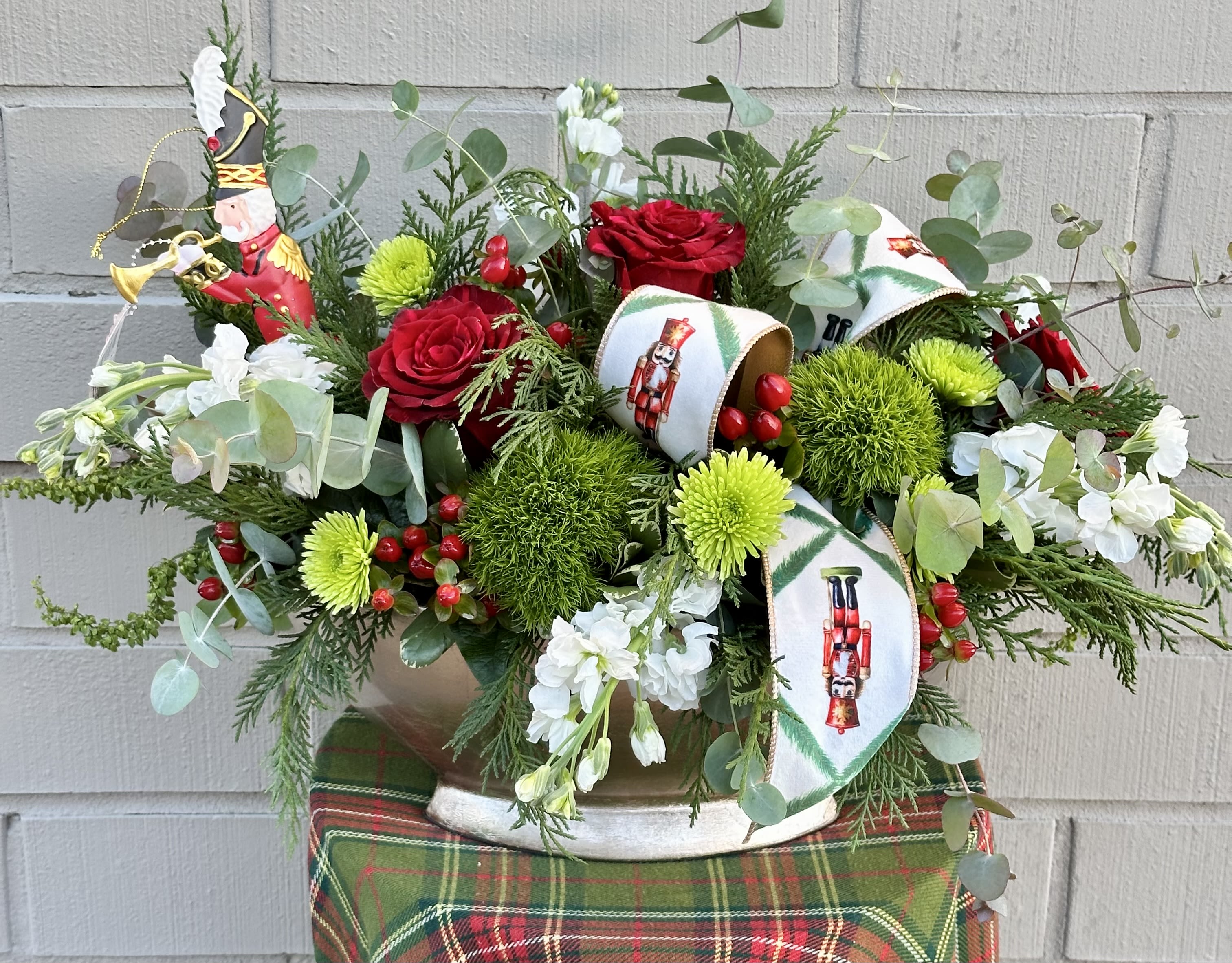 Nutcracker Delight  - Enjoy This Nutcracker Inspired Christmas Arrangement with a Mixture of  Red, Green, and White Flowers, Dressed With Nutcracker Ribbon and a  Metal Nutcracker Ornament. Arrives in a Ceramic Gold and Cream Container. 