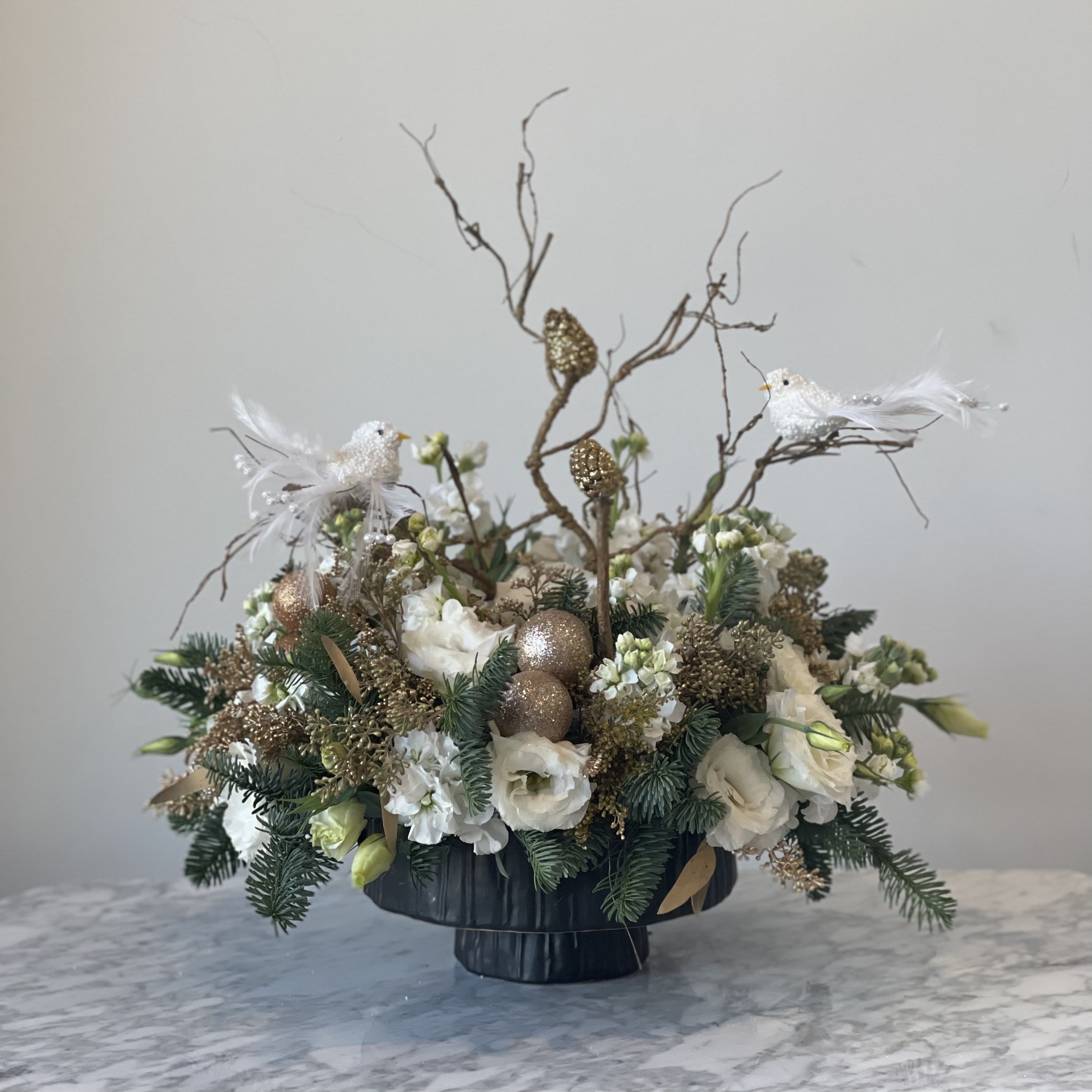 Winter Bliss - Made in a beautiful black vase with gold accents. The white bird could be replaced by another toy.  Standard - pictured Deluxe - the size of the arrangment will be bigger Premium - more premium flowers would be added to the arrangement