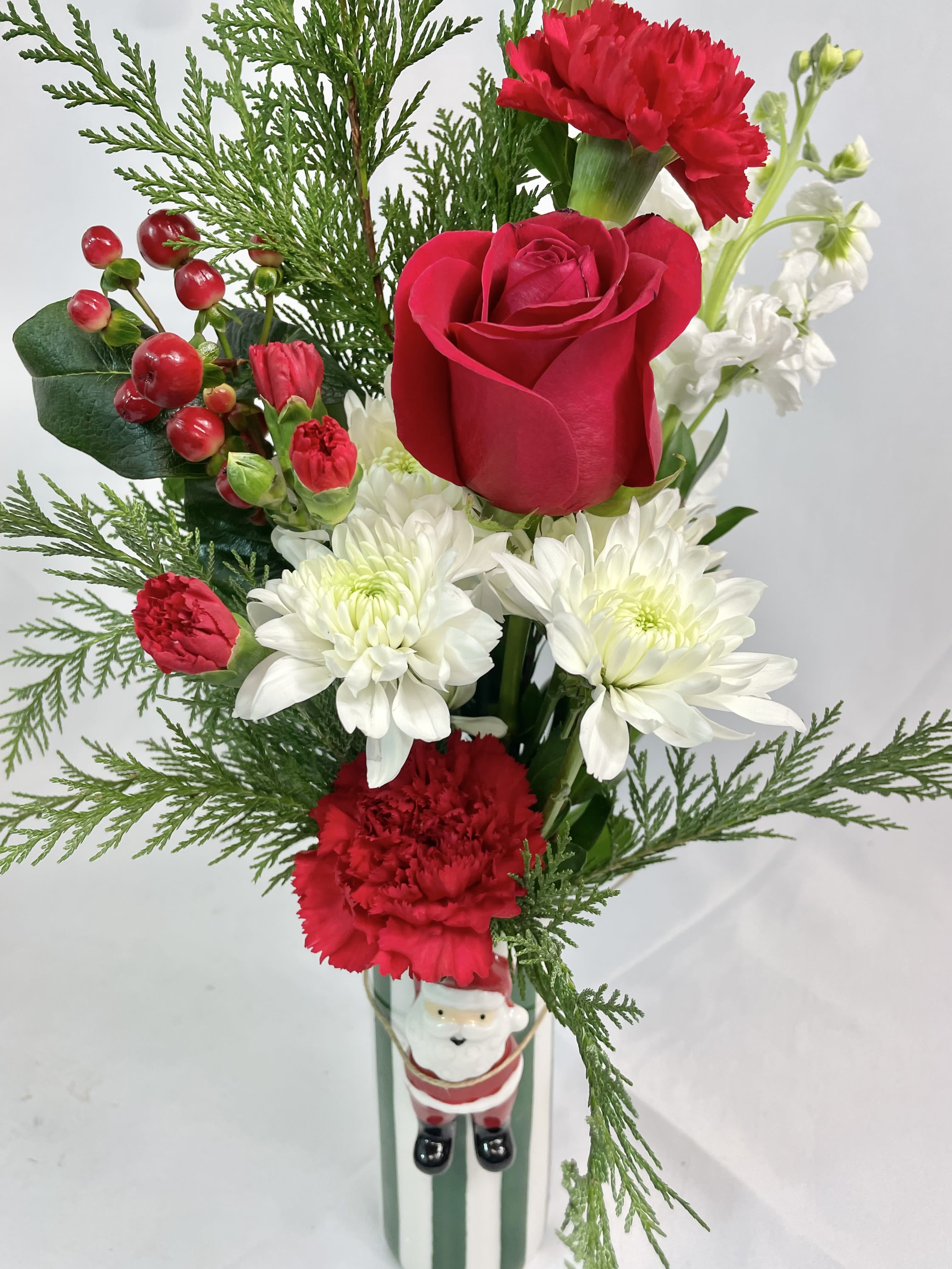 Holly Jolly Santa Flowers - A holly jolly bouquet with a keepsake, ceramic, striped vase with Santa! Fresh Cedar with red berries, Roses, Stock and Chrysanthemums. A gift sure to bring jolly smiles! 