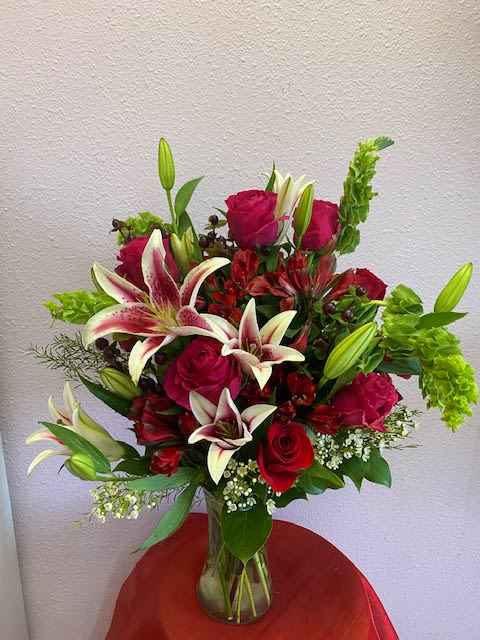 Sweetness And Reds by Forever Flowers - Half dozen Sweetness roses, -white with pink tipped petals and stargazers with red berries and bells of Ireland in a clear tall vase.