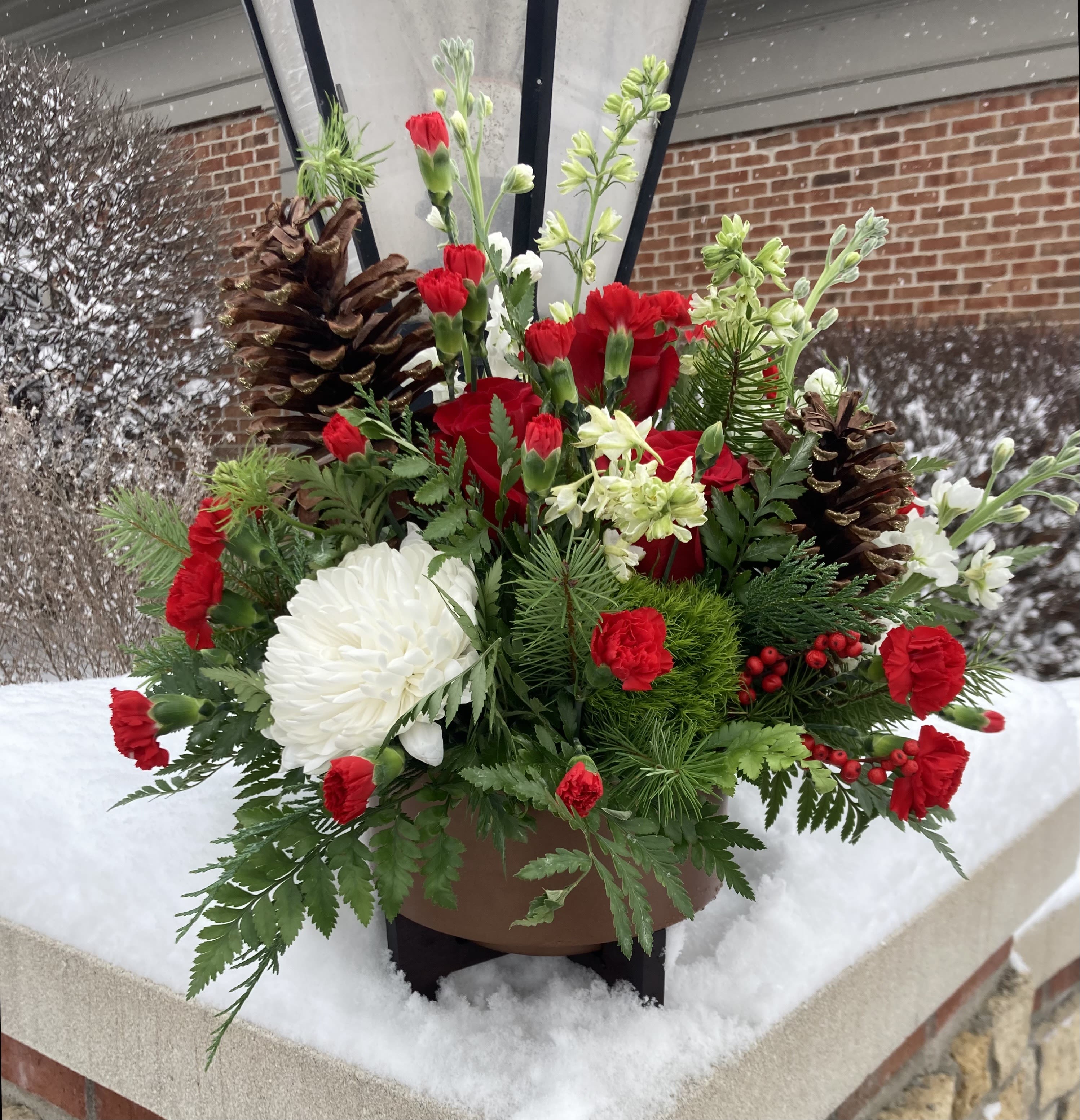 Warm Tidings - This grand arrangement will make the perfect centerpiece for any holiday party. Featuring red and white florals and finished with fragrant pine. 