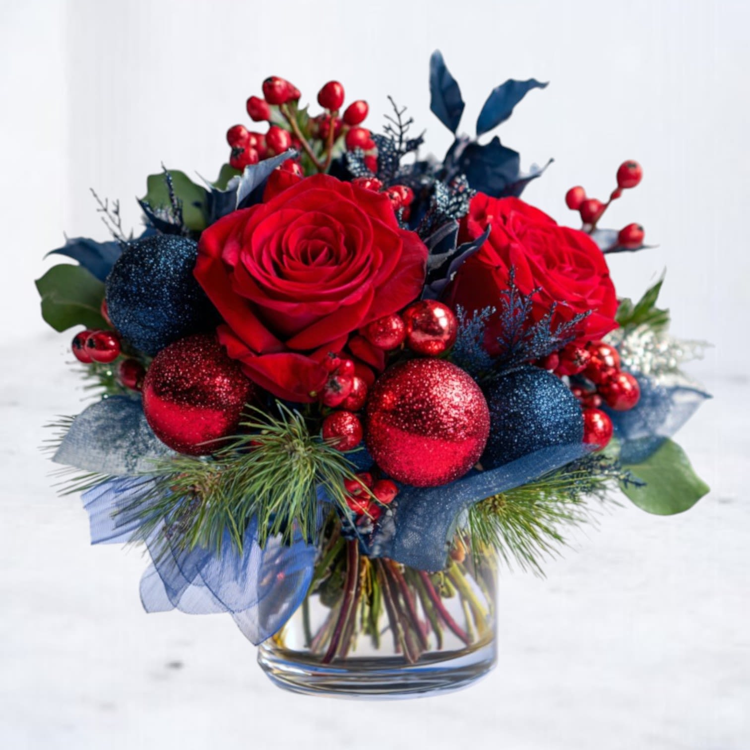 Midnight Merriment - Bring bold holiday drama to your table with Midnight Merriment, a small but striking Christmas arrangement designed in vivid reds, deep midnight blues, and sparkling seasonal accents. Lush premium red roses, festive berries, and holiday greenery are paired with navy and crimson glitter ornaments for a playful, modern twist on traditional Christmas décor.  Hand-designed in a clear glass vase, this compact yet lush arrangement is perfect for holiday dinners, gifting, office celebrations, or adding a pop of color to your home this season.  Whether you’re decorating for Christmas Eve, hosting holiday brunch, or sending a unique festive surprise, Midnight Merriment delivers color, cheer, and a dash of sparkle—without feeling ordinary.  Available for same-day flower delivery in Magnolia, The Woodlands, Montgomery, Conroe, Tomball, and surrounding Houston areas.