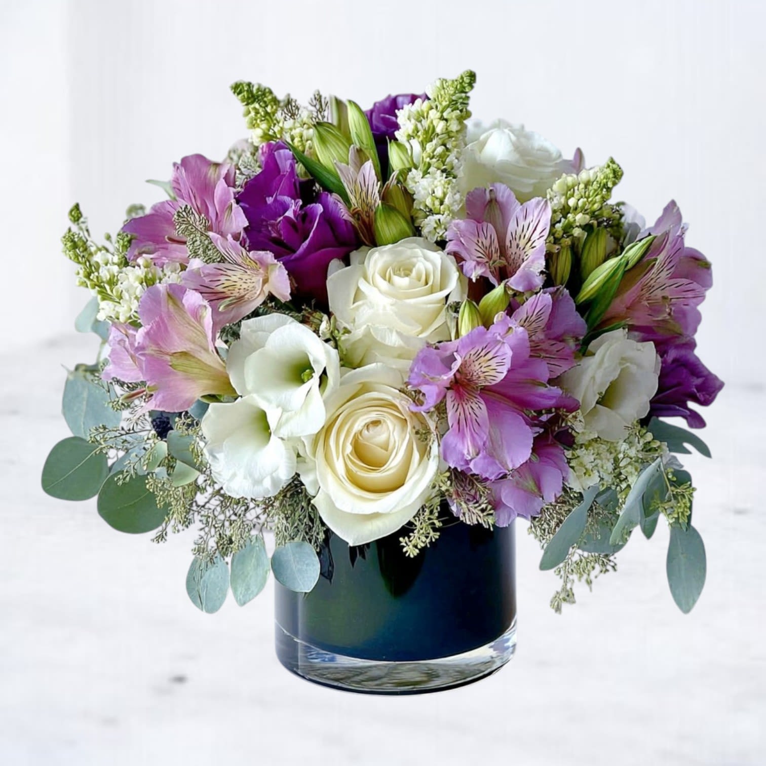 Meadow Mist Bouquet - Bring a touch of nature’s gentle charm into any day with our Meadow Mist Bouquet. This everyday arrangement pairs soft ivory roses and white lilies with delicate purple alstroemeria and lisianthus, creating a fresh blend of elegance and cheer. Accented with eucalyptus and lush greenery, it’s the perfect gift for birthdays, anniversaries, thank-yous, or simply to brighten someone’s home.  Available for same-day flower delivery in Magnolia, The Woodlands, Spring, and Montgomery, TX, this bouquet is designed with premium seasonal blooms for lasting beauty.