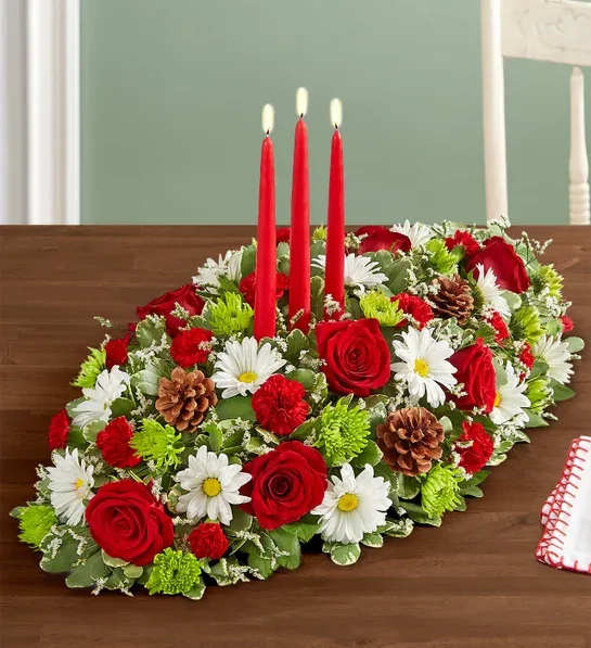 Season’s Greetings™ Centerpiece - Send season’s greetings in classic style. Our charming Christmas centerpiece is hand-arranged with classic holiday blooms and decorated with delightful accents. Tapered candles add to the elegance of this traditional design, sure to bring joy into the hearts and homes of family and friends.