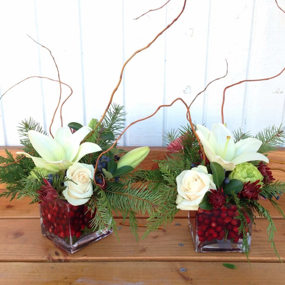 Holiday Cranberry Duo - A petite set of two (2) cubed arrangements, set in real fresh cranberries with Christmas greens and winter blooms, embellished with curly willow. Great for coffee tables, night stands, or a duo on a dining table. Our way of incorporating fruits into arrangements! 