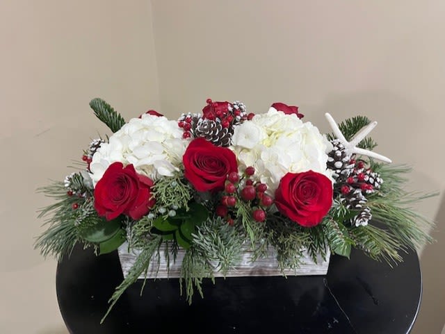 Nautical Christmas  - Long and low arrangement in a white washed wooden box filled with holiday greens, red roses, white hydrangeas, hypericum berries and pinecones and a starfish ornament.