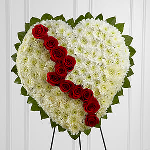 Broken Heart - YRR is a beautiful way to express the impact that the departed had on your life. Pearly white chrsyanthemums form the shape of a heart accented with greens lined around the outside and "broken" in the middle with a line of rich red roses to create an exqusite way to honor the life of the deceased at their memorial service. Displayed on a wire easel.