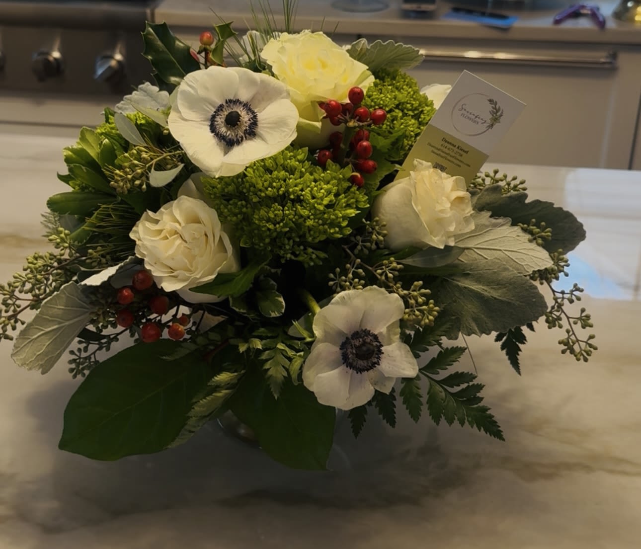 Winter in Bloom - Beautiful seasonal white flowers mixed with red berries and fresh pine.The perfect centerpiece for any table